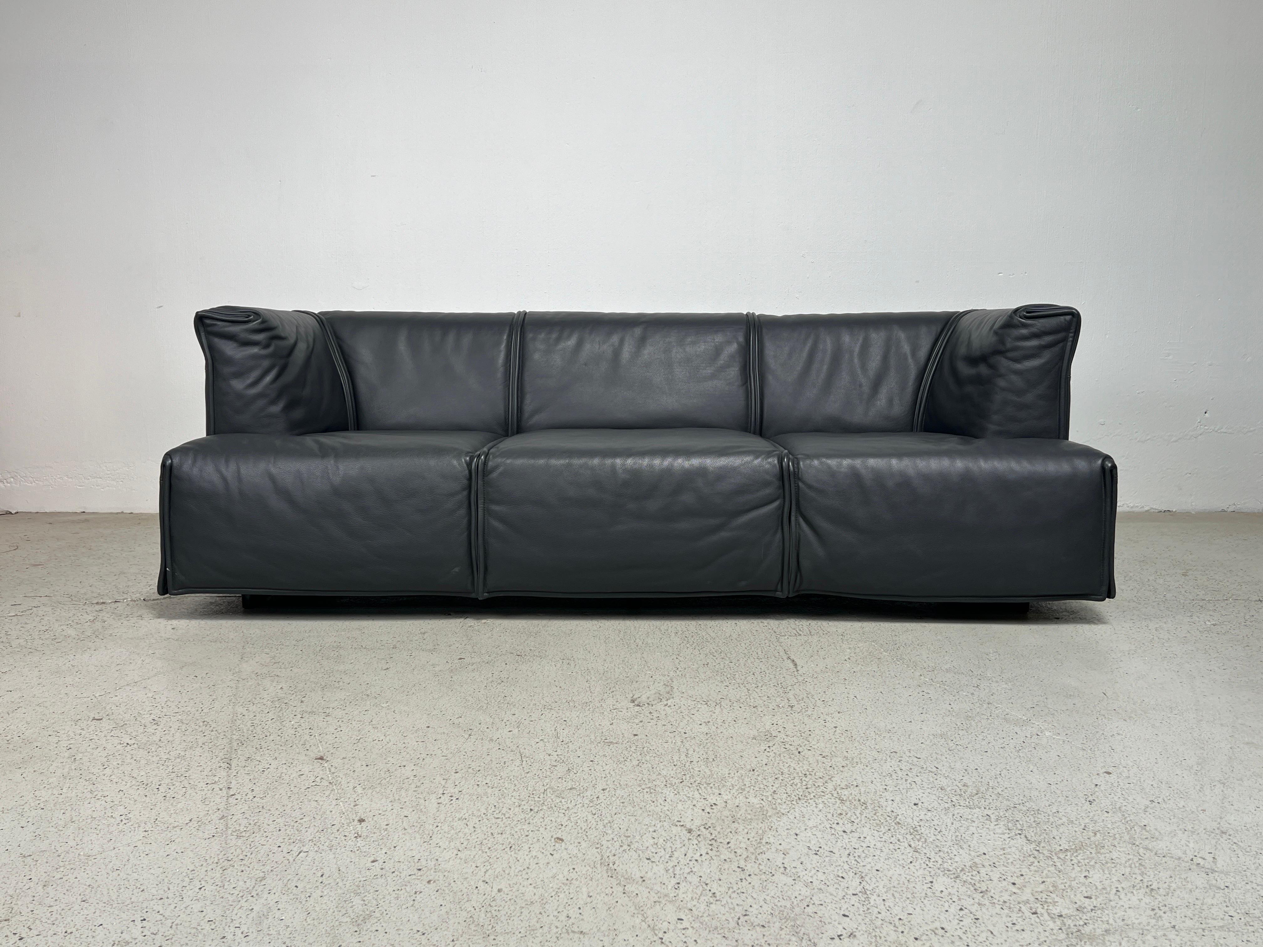 Il divano 'Cardigan' in pelle grigia, splendidamente realizzato su misura, è stato disegnato da Vico Magistretti per Cassina. 