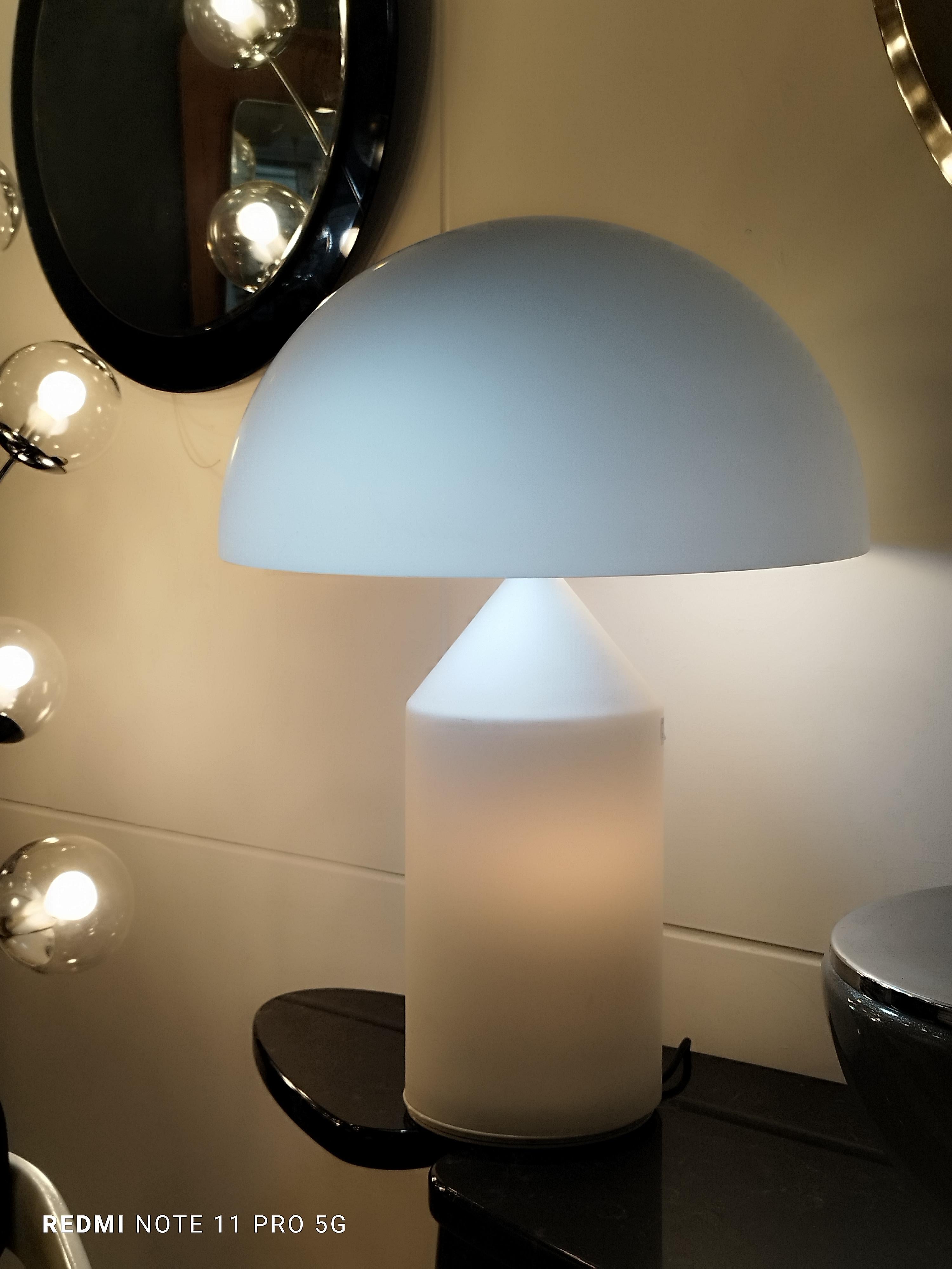 Lampe de table à lumière directe et diffuse en verre opalin de Murano. Conçue en 1977 par Vico Magistretti, Atollo est devenue au fil des ans l'archétype de la lampe de table, remportant le Compasso d'Oro en 1979, et révolutionnant complètement la