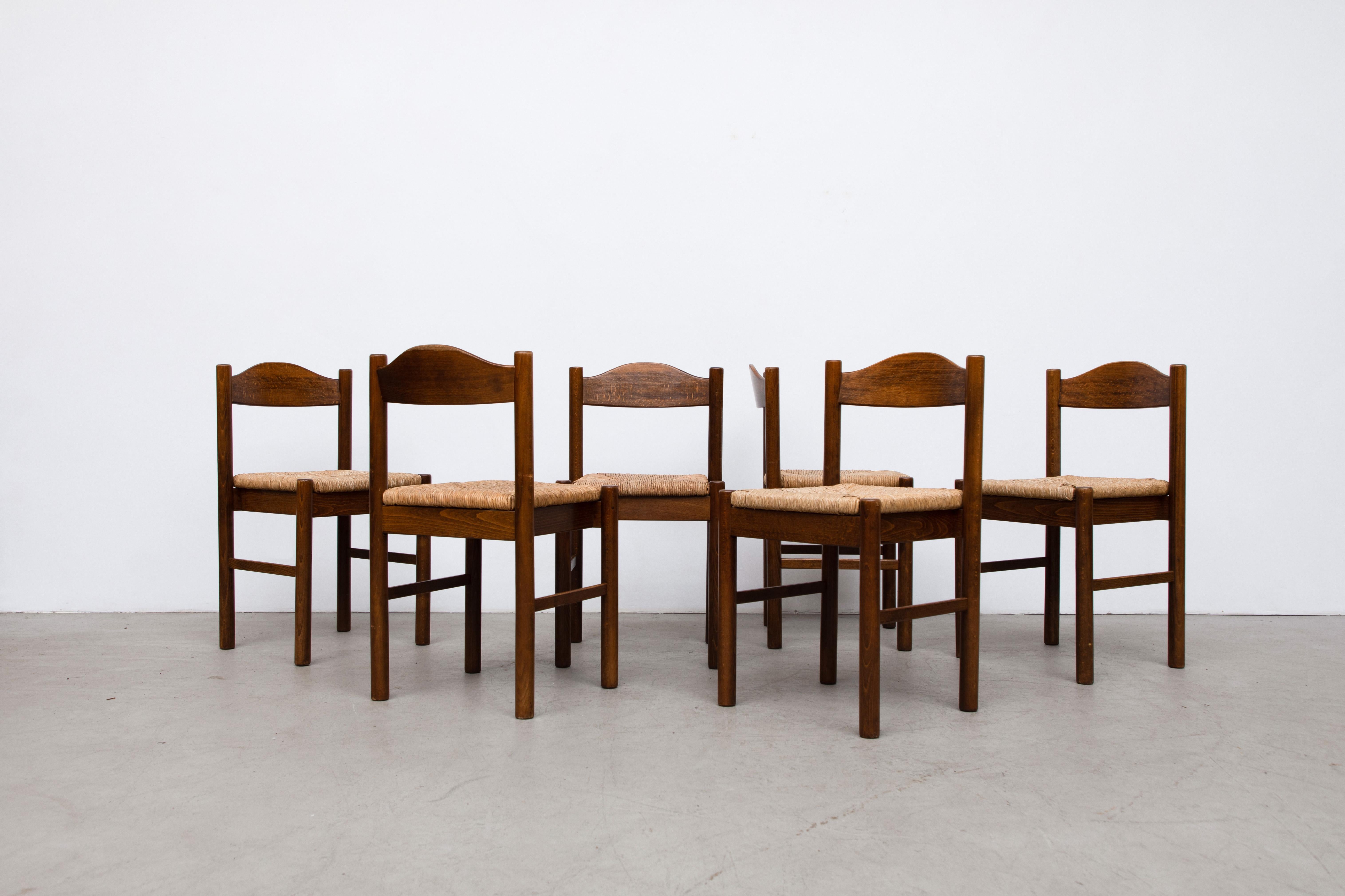 Vico Magistretti Inspired Wood and Rush Dining Chairs. Stackable if needed. In good original condition with wear and patina consistent with their age and use. A similar set of 8 available with a decorative carving in the seat backs. Listed