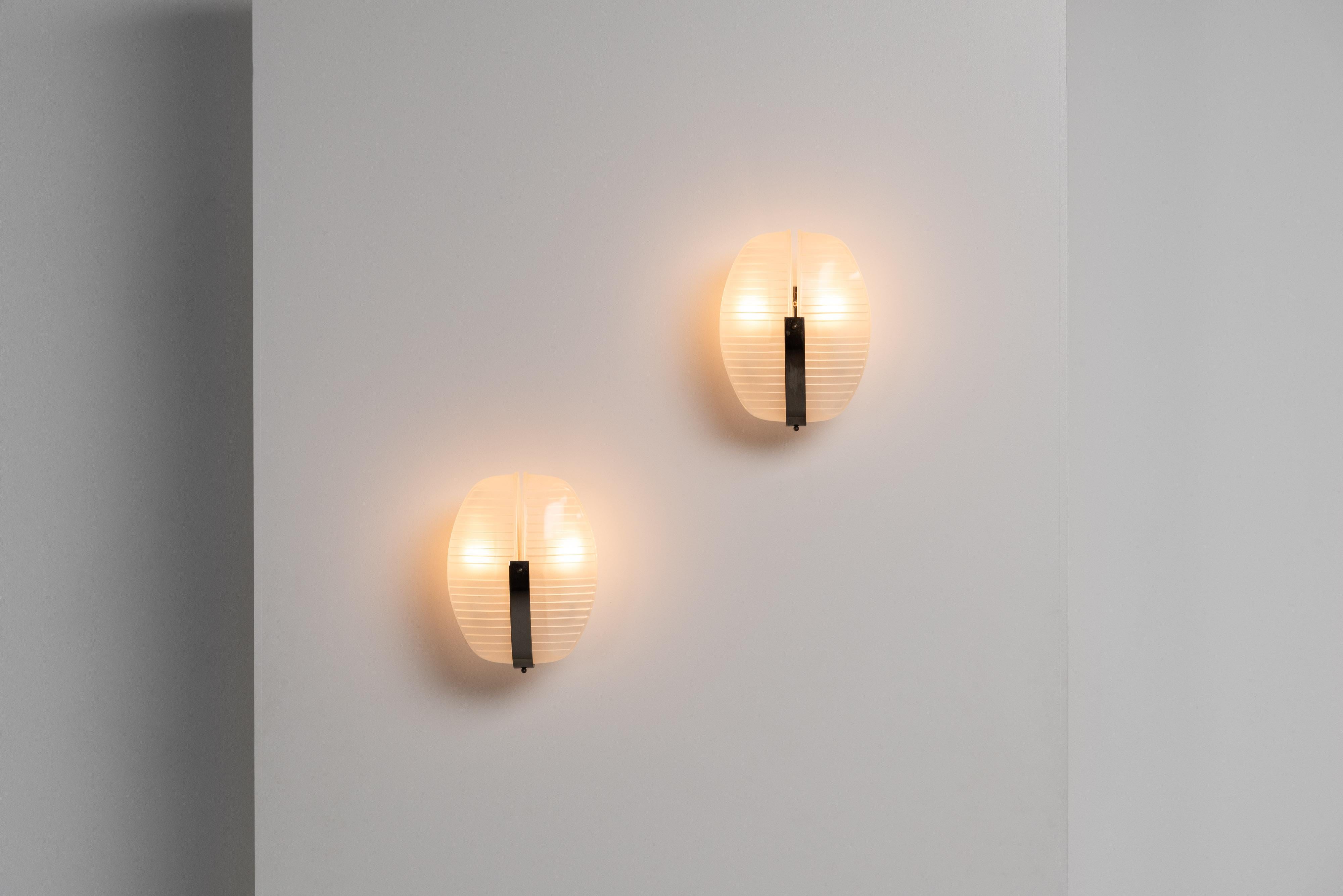 Wonderful Lambda wall sconces designed by Vico Magistretti and manufactured by Artemide in Italy in 1961. When these lamps are turned on, they have a charming industrial look, thanks to the ribbed glass shades with frosted insides. They are