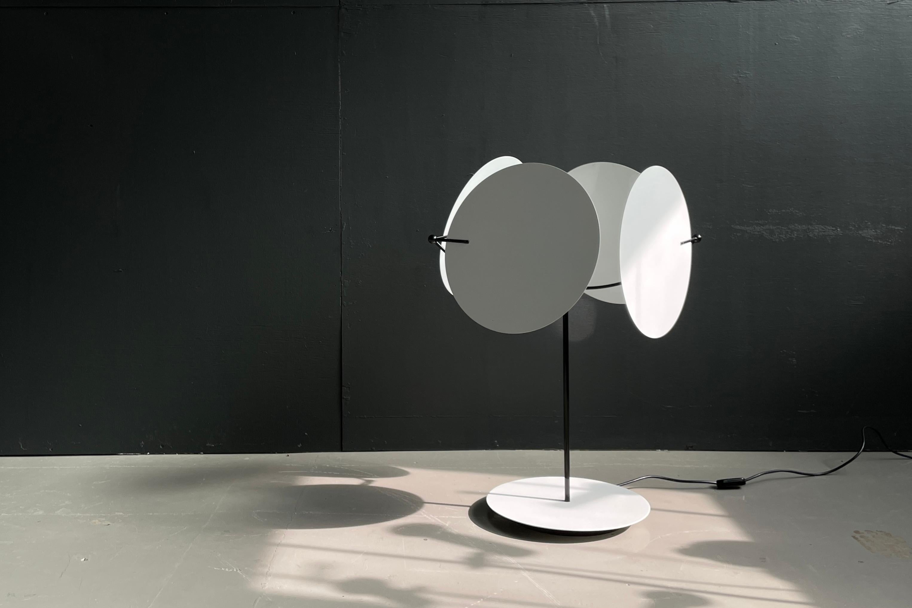 L'architecte Vico Magistretti a conçu la série Monet en 1980. Cette pièce à 4 nuances peut être utilisée comme lampe de sol ou de table. Tous les stores peuvent être orientés selon différents angles pour diriger la lumière et l'ombre. Excellente
