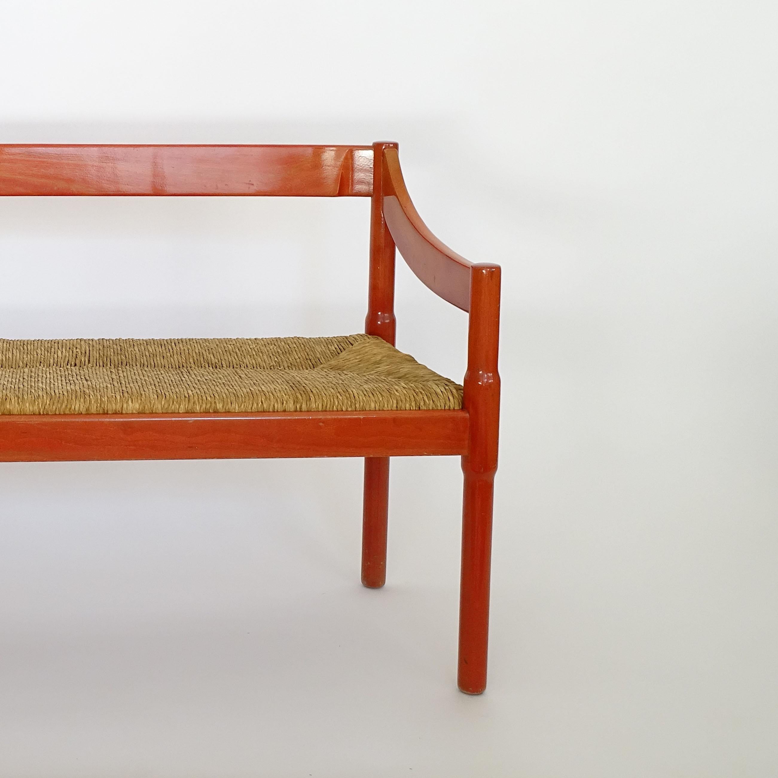 Magnifique banc Vico Magistretti Carimate avec une patine rouge d'origine magnifiquement vieillie et une assise en paille d'origine.
Fabriqué par  Cassina, Italie, 1958