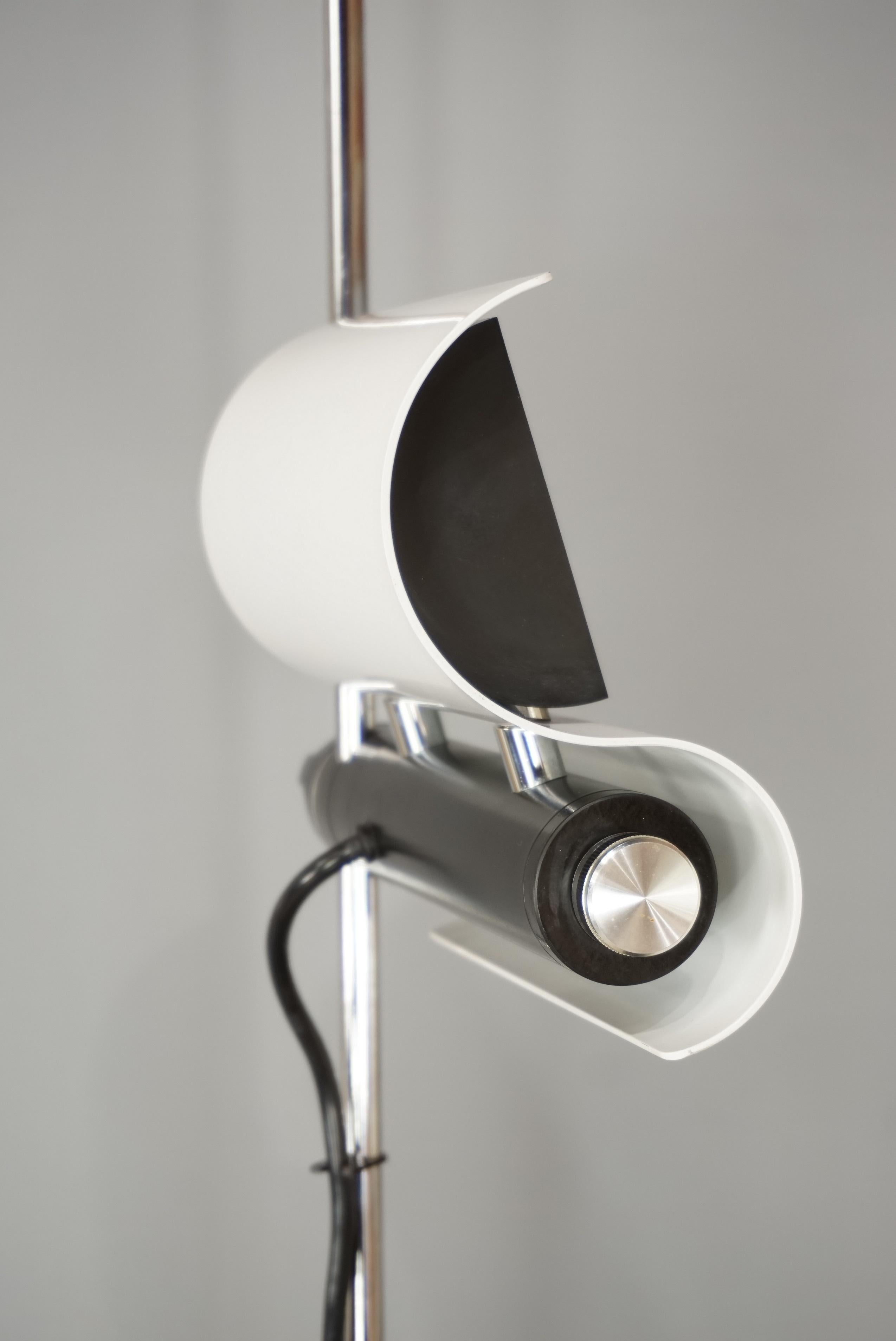 Aerial and poetic this floor lamp of the 1970s design by Vico Magistretti! It is composed of a central rod in chrome-plated metal, a base (diameter 30 cm) in white lacquered metal, an adjustable halogen receptacle adjustable in height along the rod