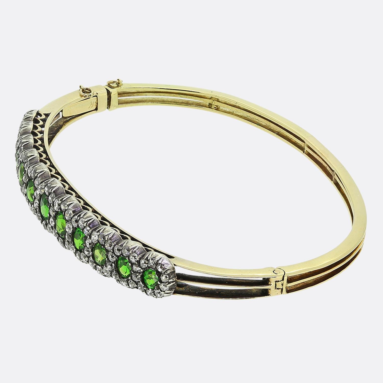 Here we have a fabulous 18ct yellow gold bangle taken the from the Victorian era. This antique piece has been adorned with eleven round faceted vibrant green demantoid stones which themselves are framed by a striking row of white old mine-cut