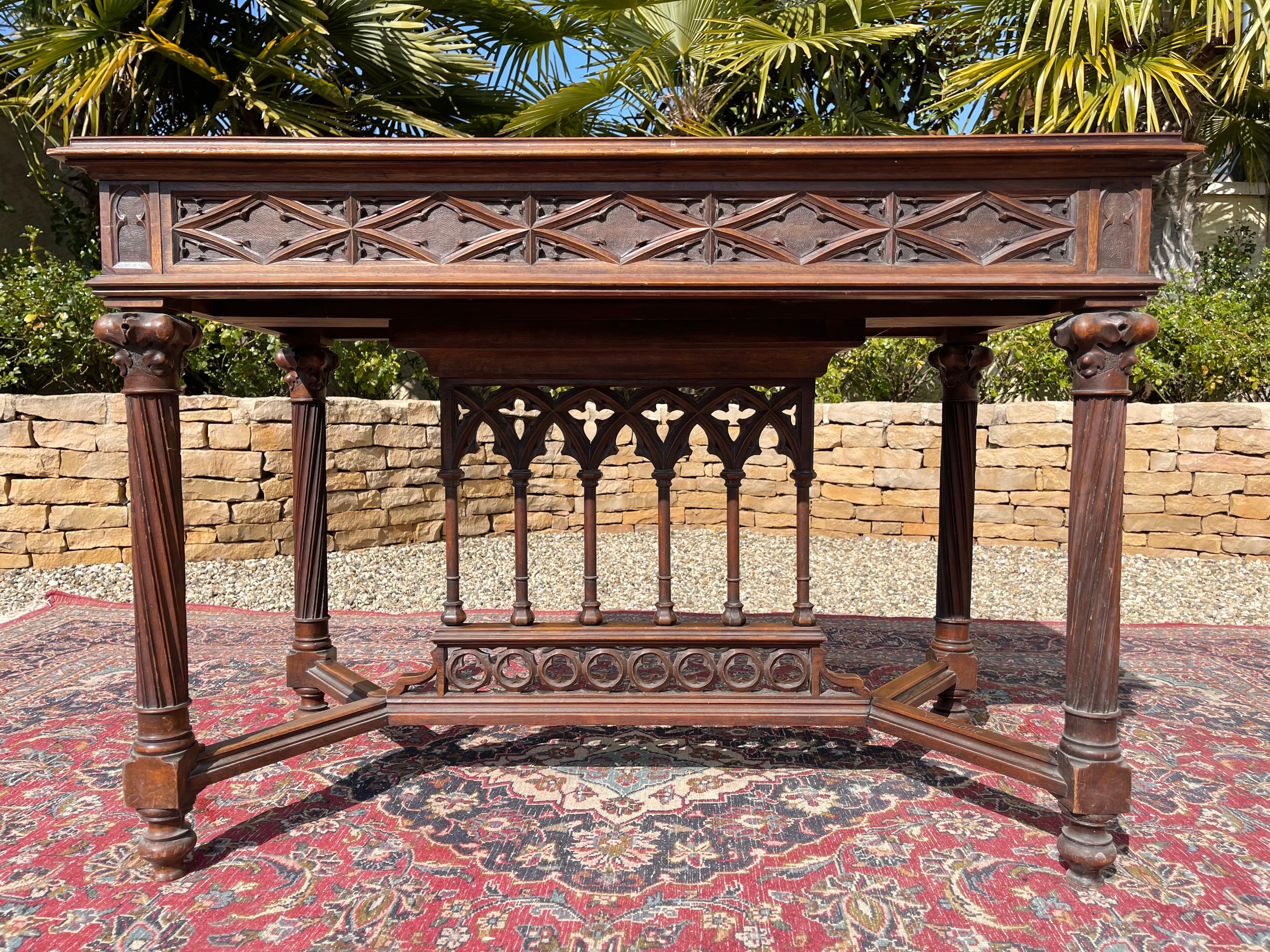 Richly carved and openwork neogothic walnut table in good condition. It is signed on the foot 