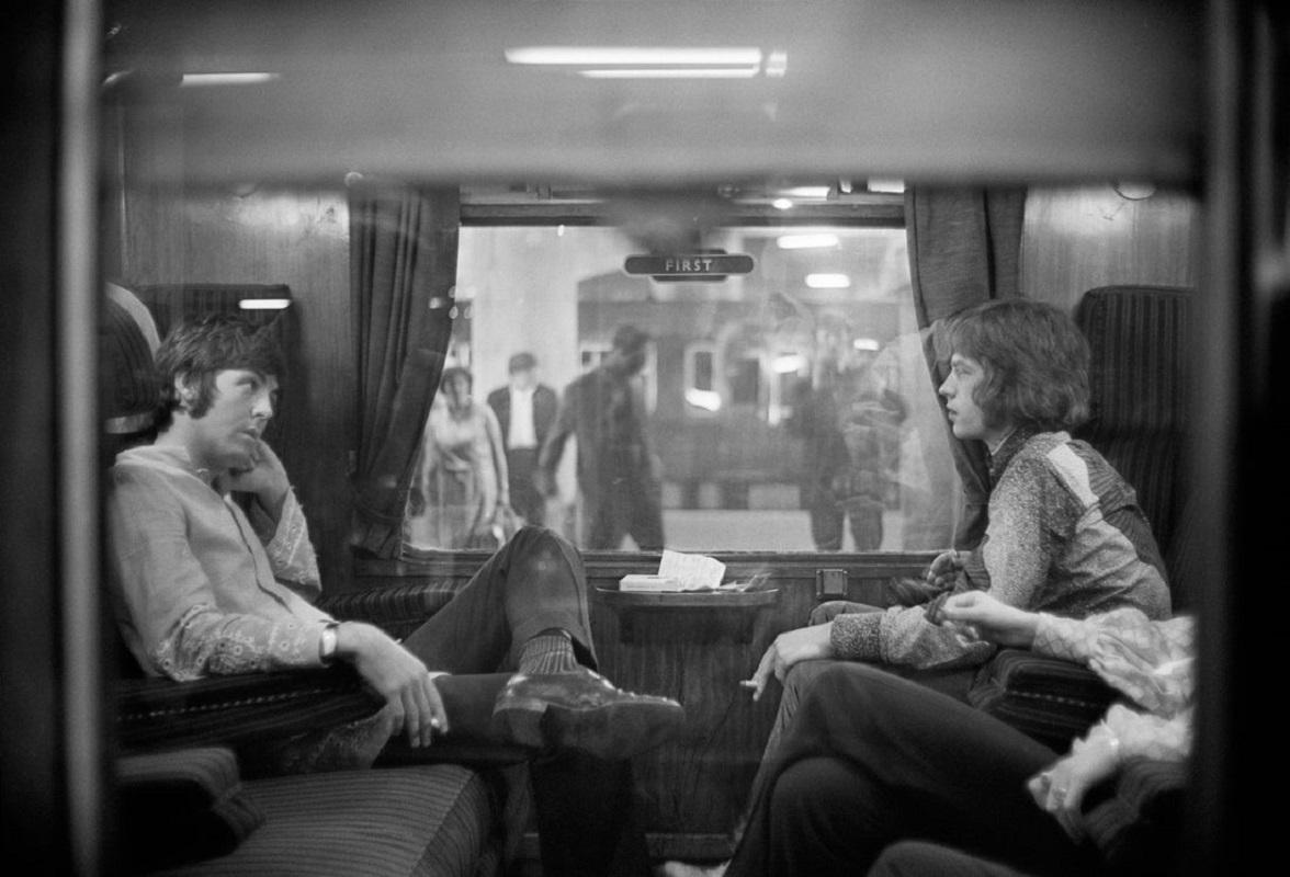 "Viaggio in prima classe" di Victor Blackman

25 agosto 1967: Paul McCartney dei Beatles e Mick Jagger dei Rolling Stones siedono l'uno di fronte all'altro su un treno alla stazione di Euston, in attesa di partire per Bangor.

Non