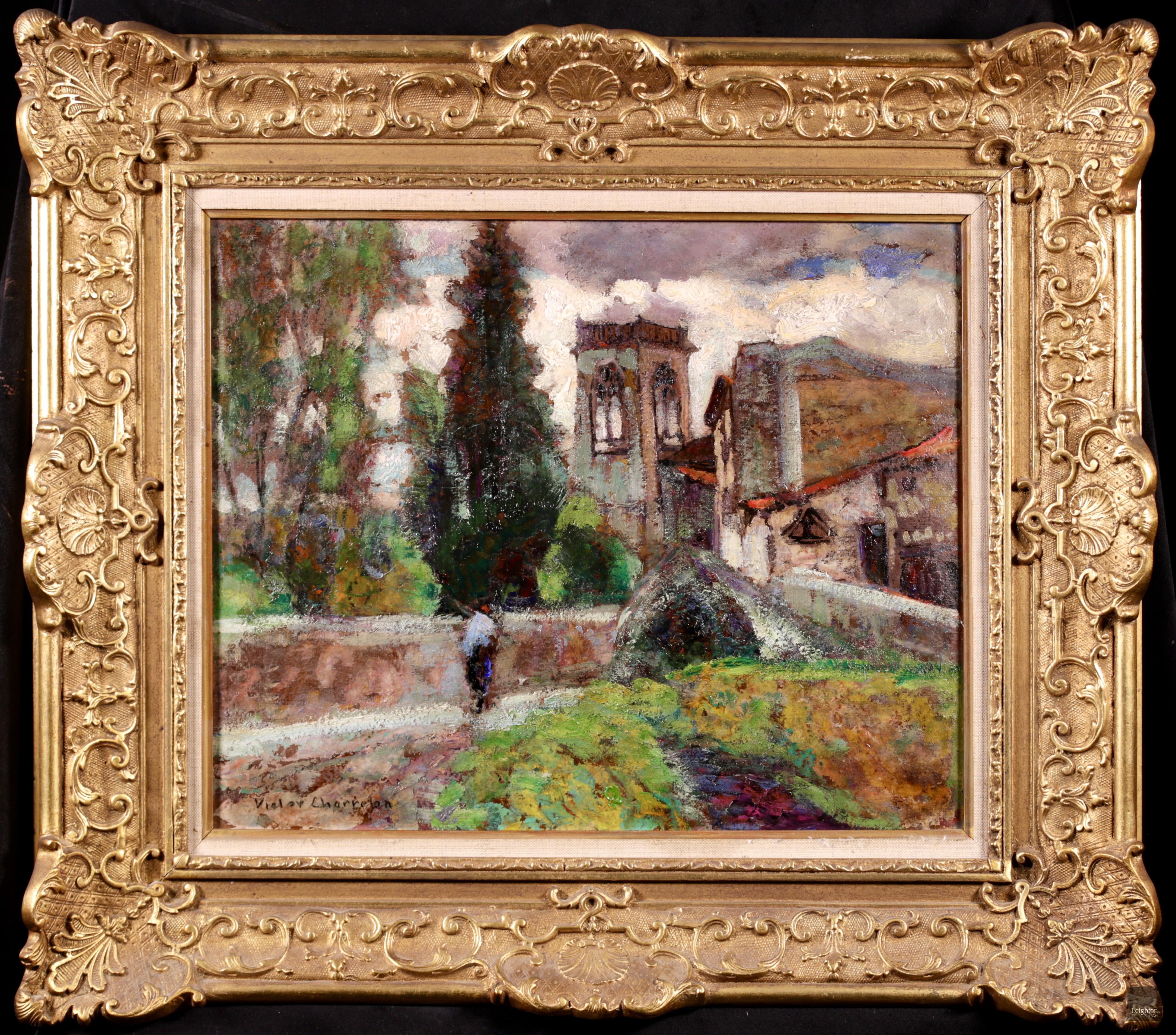Stunning signed figure in landscape oil on board circa 1920 by sought after French Post-Impressionist painter Victor Charreton. The piece depicts a man walking up a hilly path past the buildings of a French village. The path is surrounded by walled