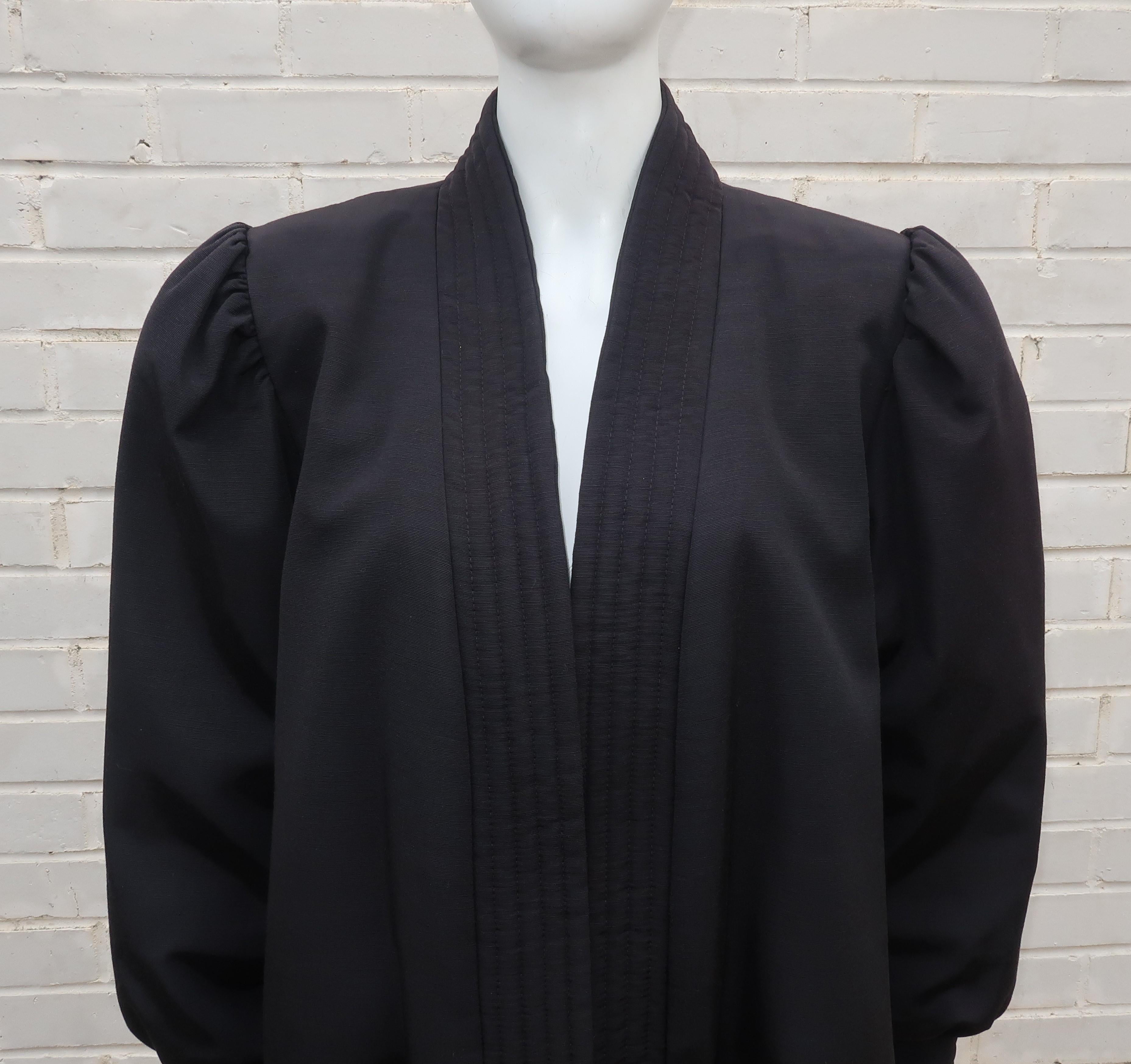 A chic 1980's Victor Costa black faille swing coat perfect for topping off evening and cocktail wear.  Constructed with an open front accented by a padded channeled trim which is also replicated at the cuffs.  The feminine puff sleeves have gentle