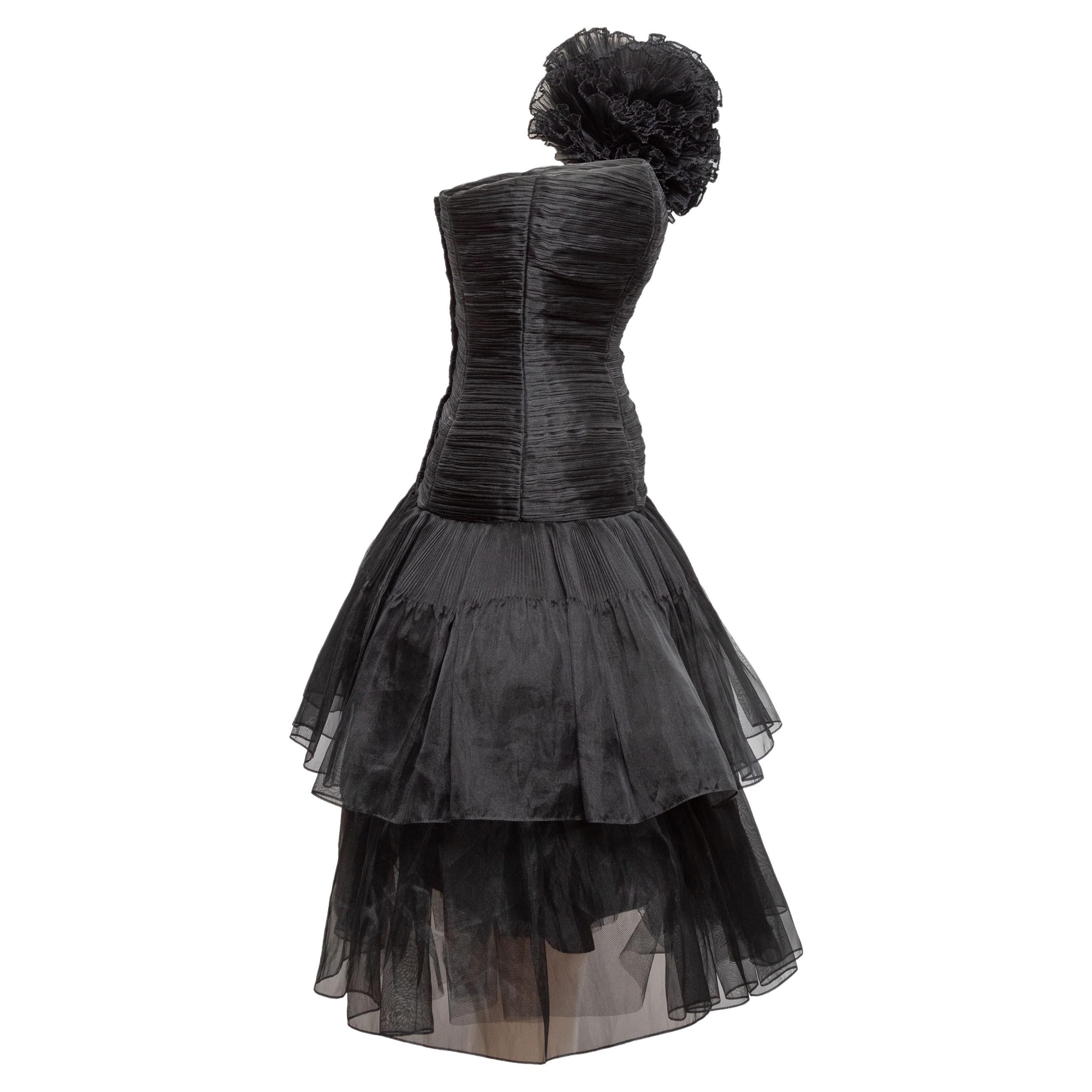 Product Details: Vintage black tulle tiered cocktail dress by Victor Costa. Ruched bodice. Rosette detailing at shoulder. Designer Size 6. Zip closure at back. 30