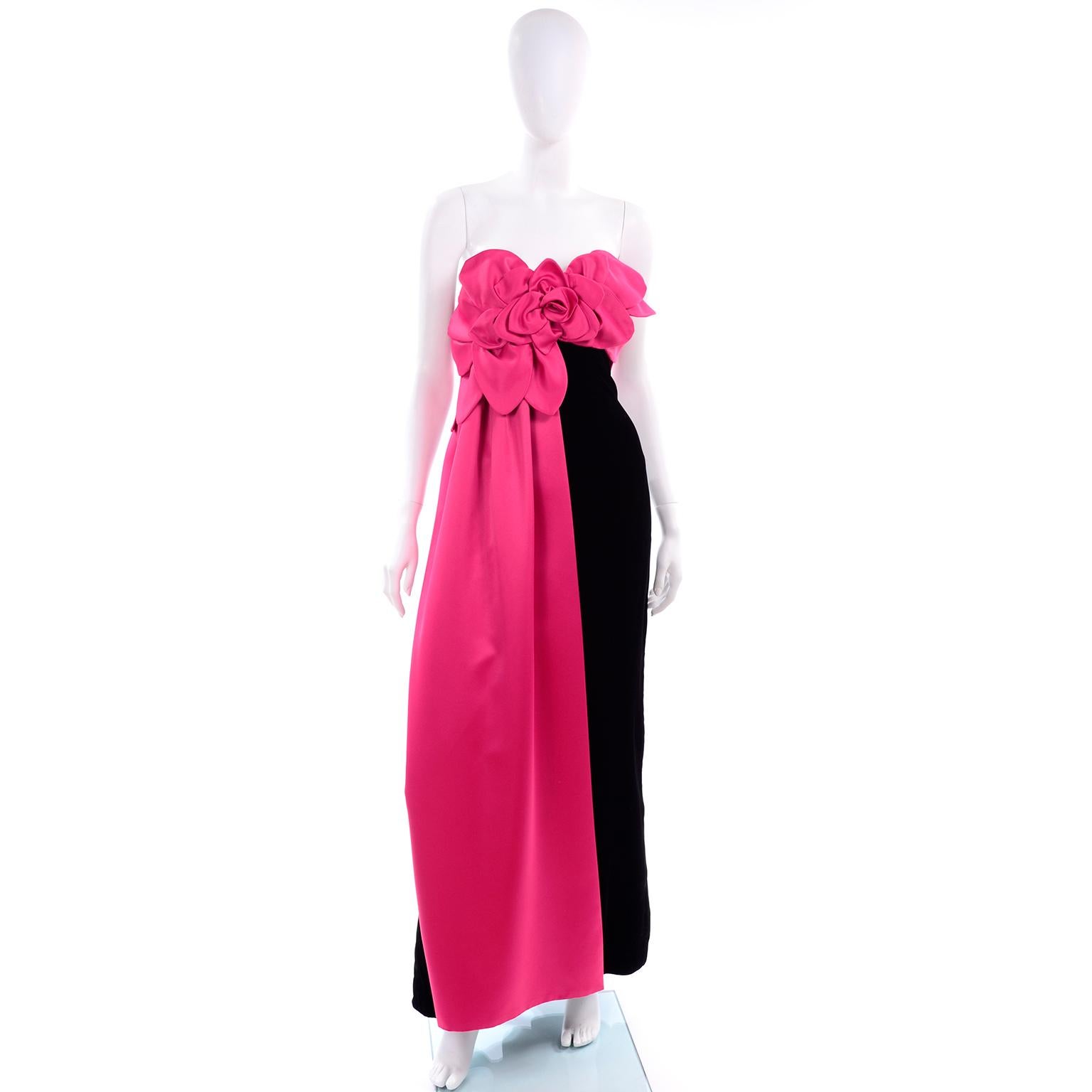 This is a sensational vintage evening gown from Victor Costa in a rich black velvet with fabulous fuschia pink satin petals and a rose on the bodice. The same pink fabric drapes down one side of the dress and the dress is fully lined in satin.  This