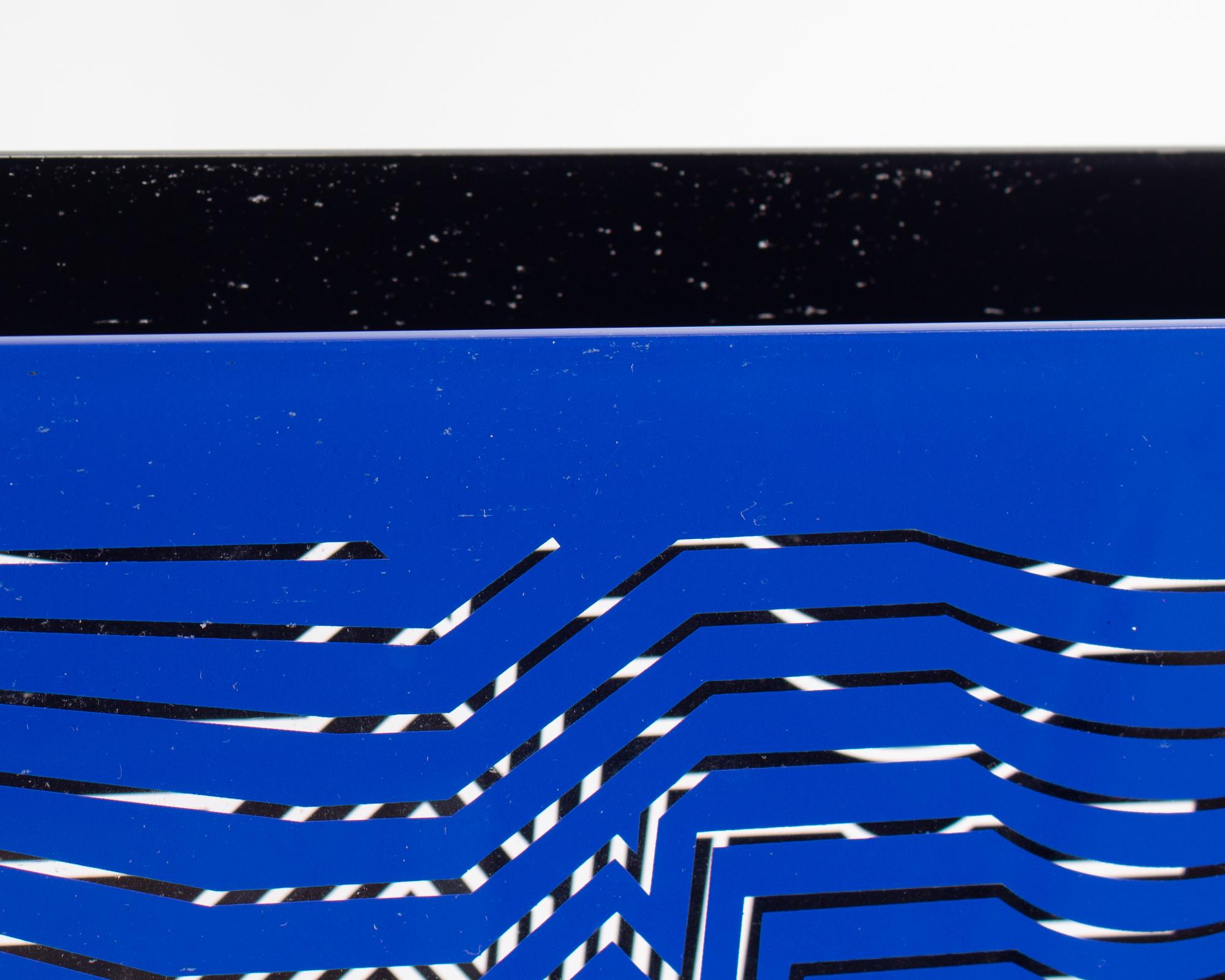 A 1981 limited edition acrylic sculpture by the Hungarian-French Op Art artist Victor Vasarely (1906-1997). This sculpture consists of two acrylic panels with geometric designs on each, one in blue and one in black, attached together by a fabric