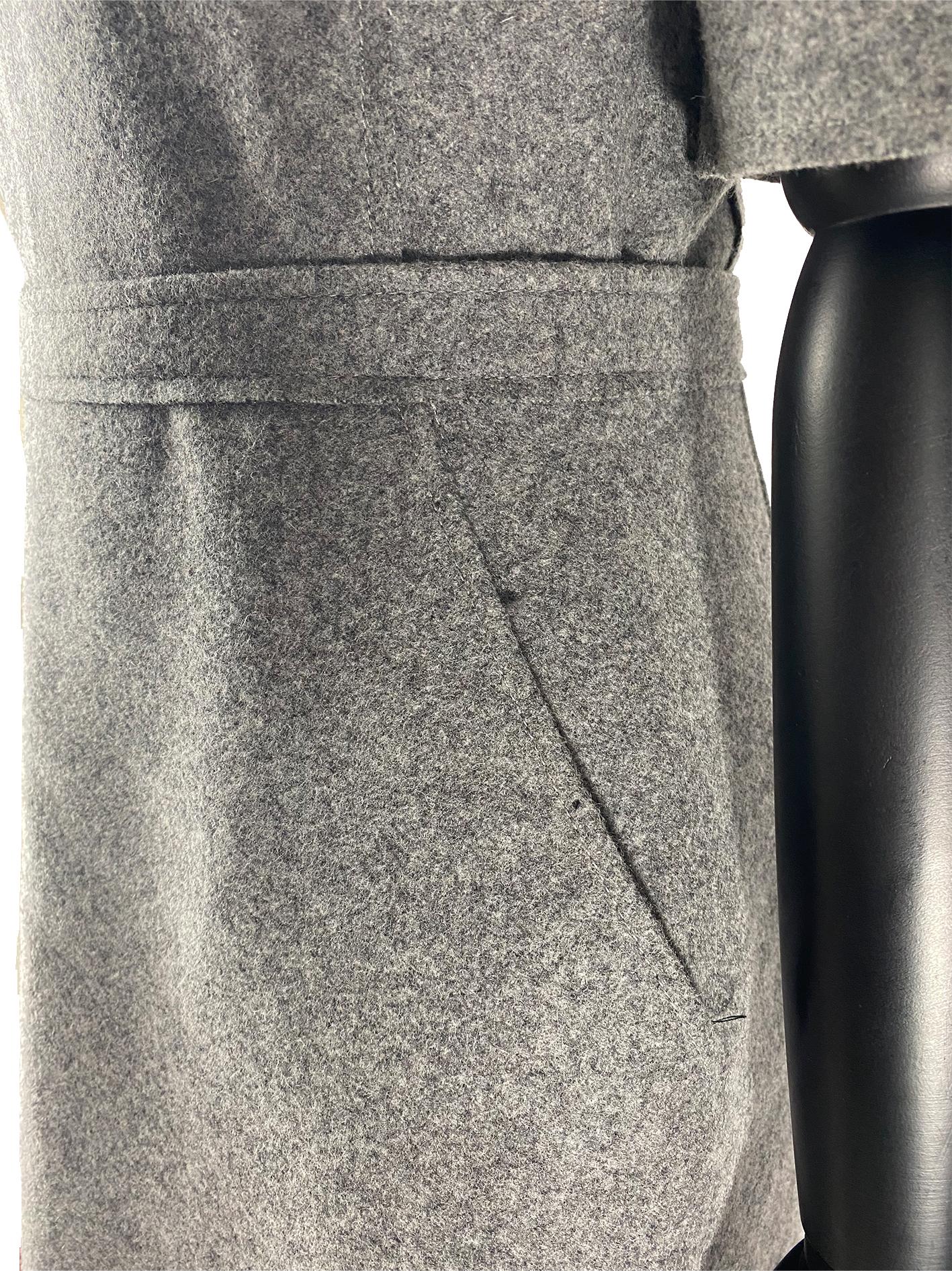 A Victoria Beckham woollen tailored shift dress in a dark marl grey with a flattering fitted bodice. The dress features a crew neckline with elbow-length sleeves. The dress is cinched at the waist with a faux waistband along with a pair of seamed