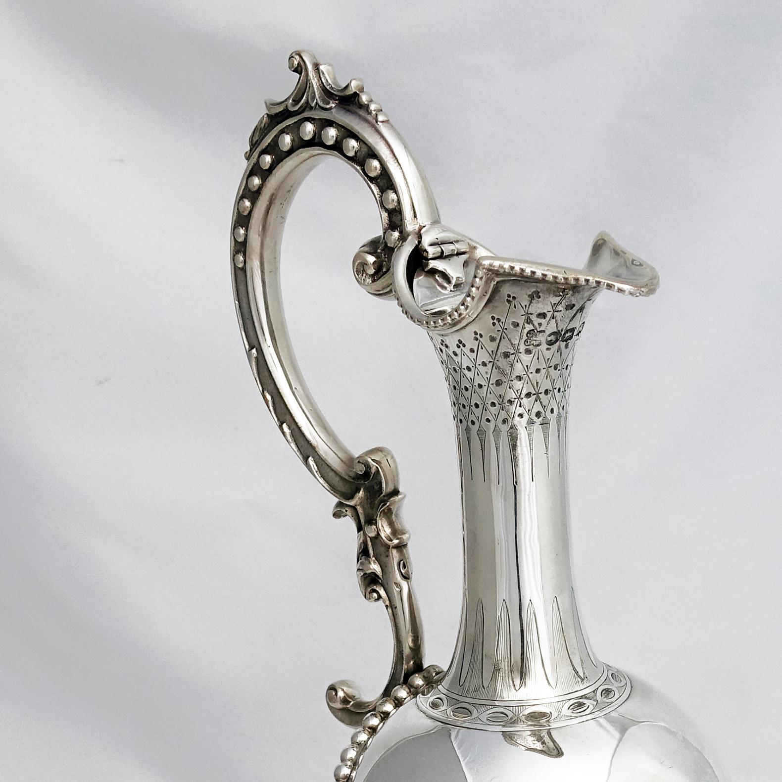 A tall Victorian English sterling silver wine ewer with the unusual hallmark of Exeter. 
This handcrafted piece has elegant strap work curving around the urn shaped body and finishing at the narrow neck.