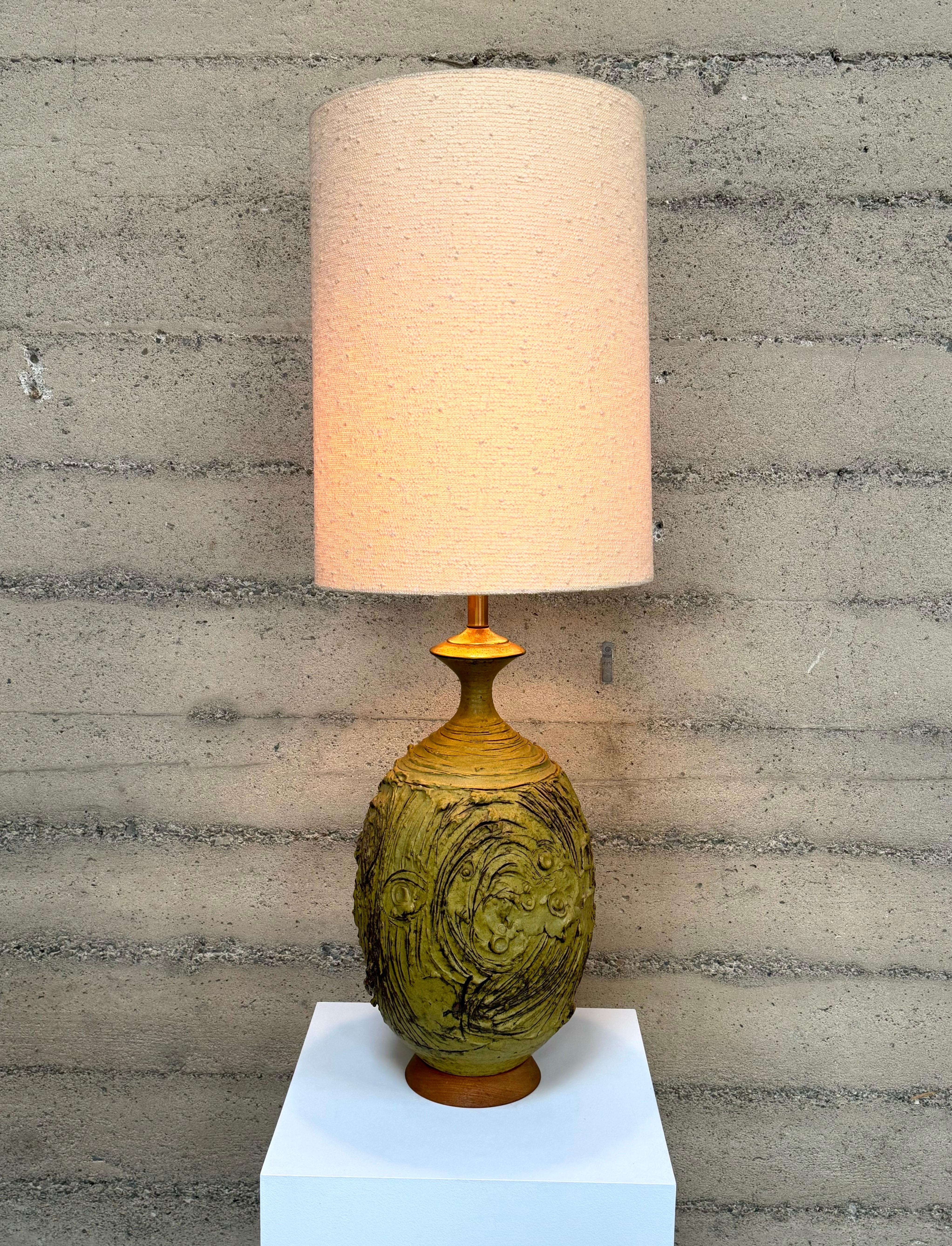 Lampe de table en grès de l'artiste céramiste californienne Victoria Littlejohn, cette lampe en céramique à la texture terreuse présente une glaçure moutarde et une base en noyer. La lampe possède l'abat-jour d'origine qui peut être inclus si vous