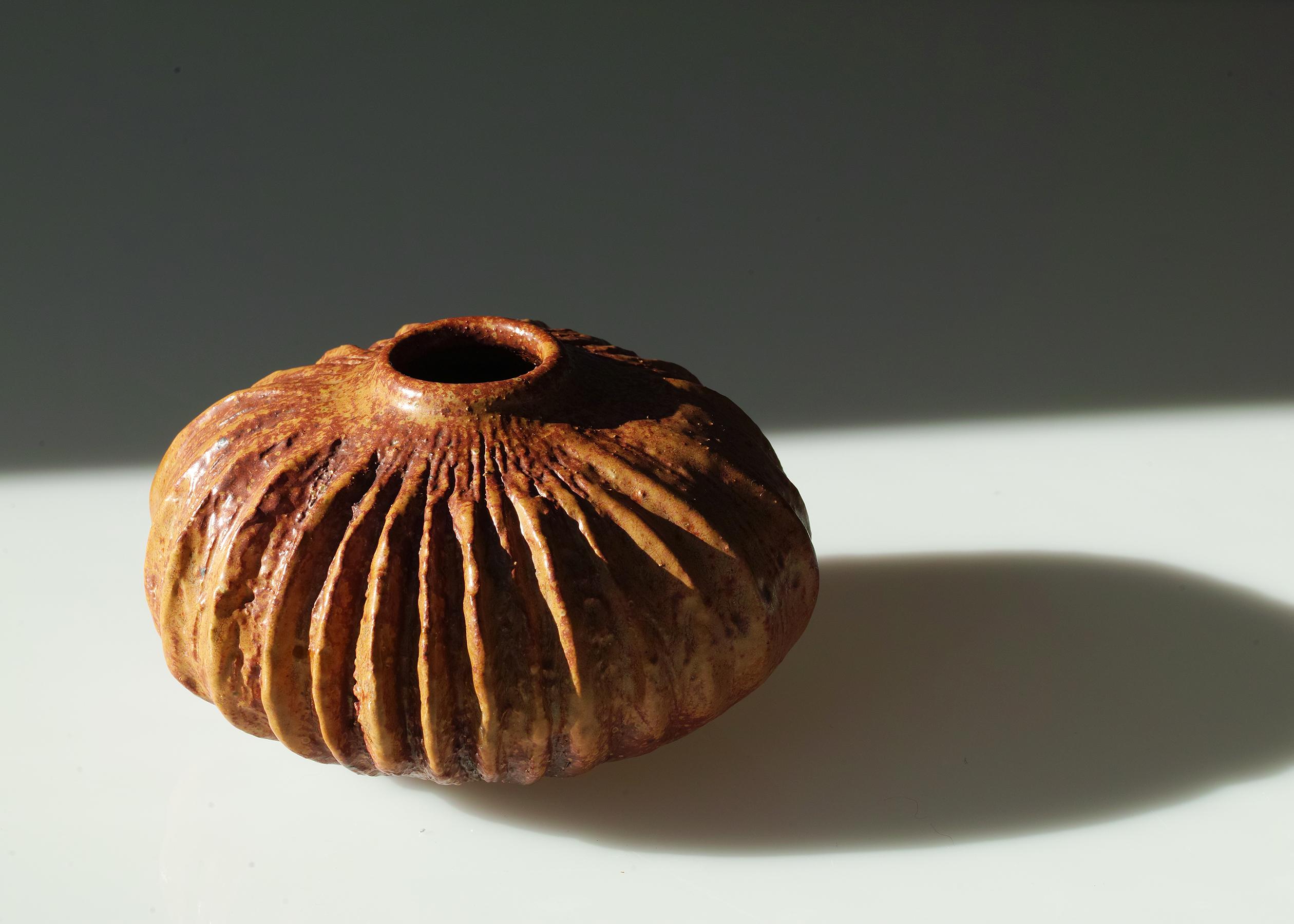 Nous vous proposons ce vase en grès de la potière californienne Victoria Littlejohn. Elle présente une forme naturaliste et organique avec un profil trapu, une surface avec des stries verticales et une glaçure aux tons naturels de la terre. 