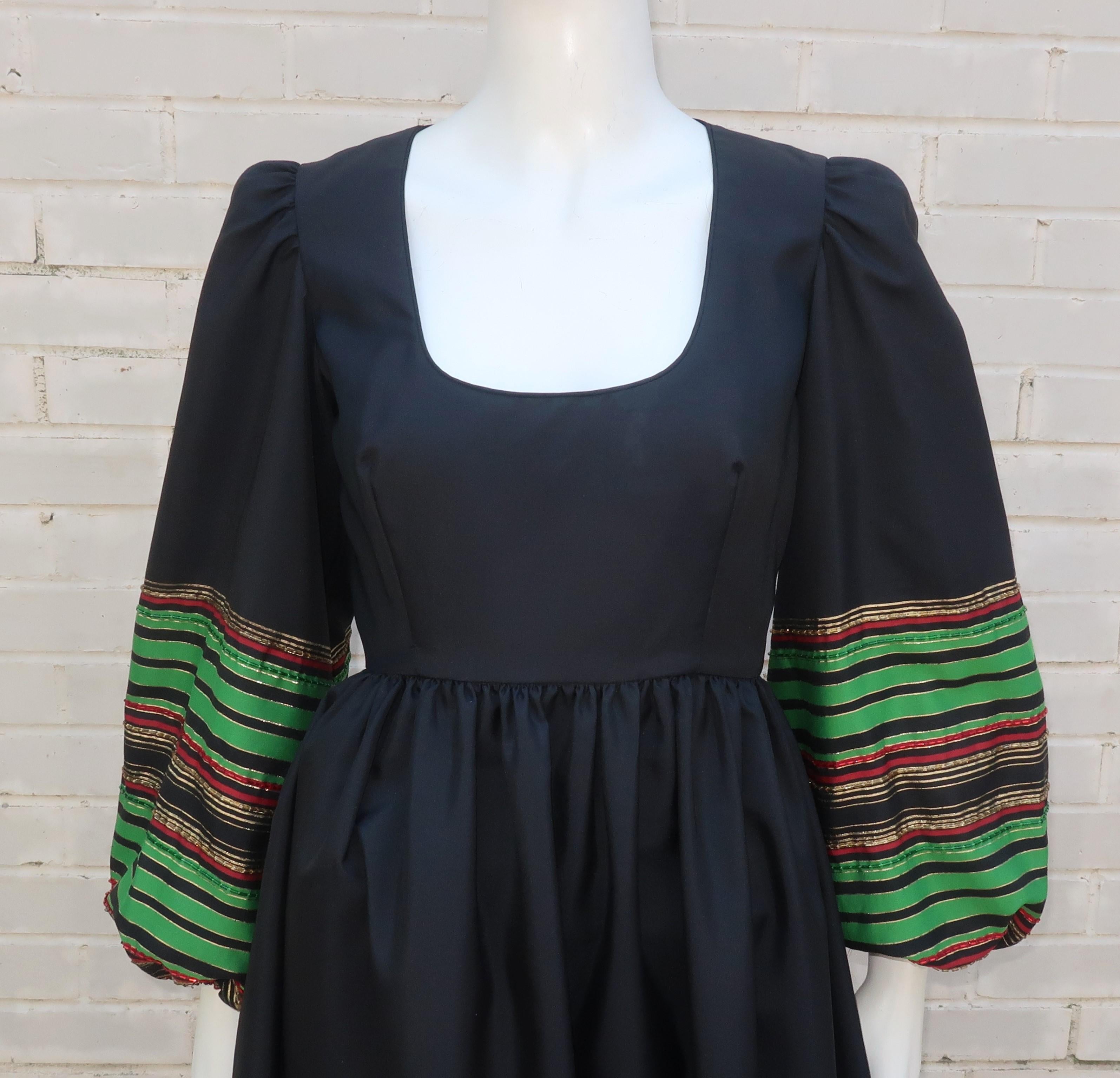 robe maxi Victoria Royal des années 1970 en taffetas noir mat avec des poignets et un ourlet rayés perlés dans des tons de lamé rouge, vert et or.  La robe se ferme à l'aide d'une fermeture éclair et d'un crochet au dos, avec une encolure dégagée,