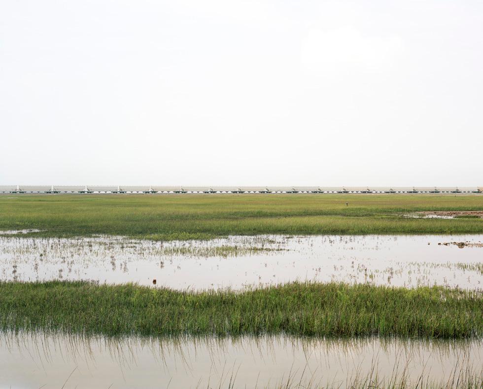 Victoria Sambunaris Landscape Photograph – Ohne Titel (Züge überqueren den Estuarial Corridor - 1), Virginia Point, Texas