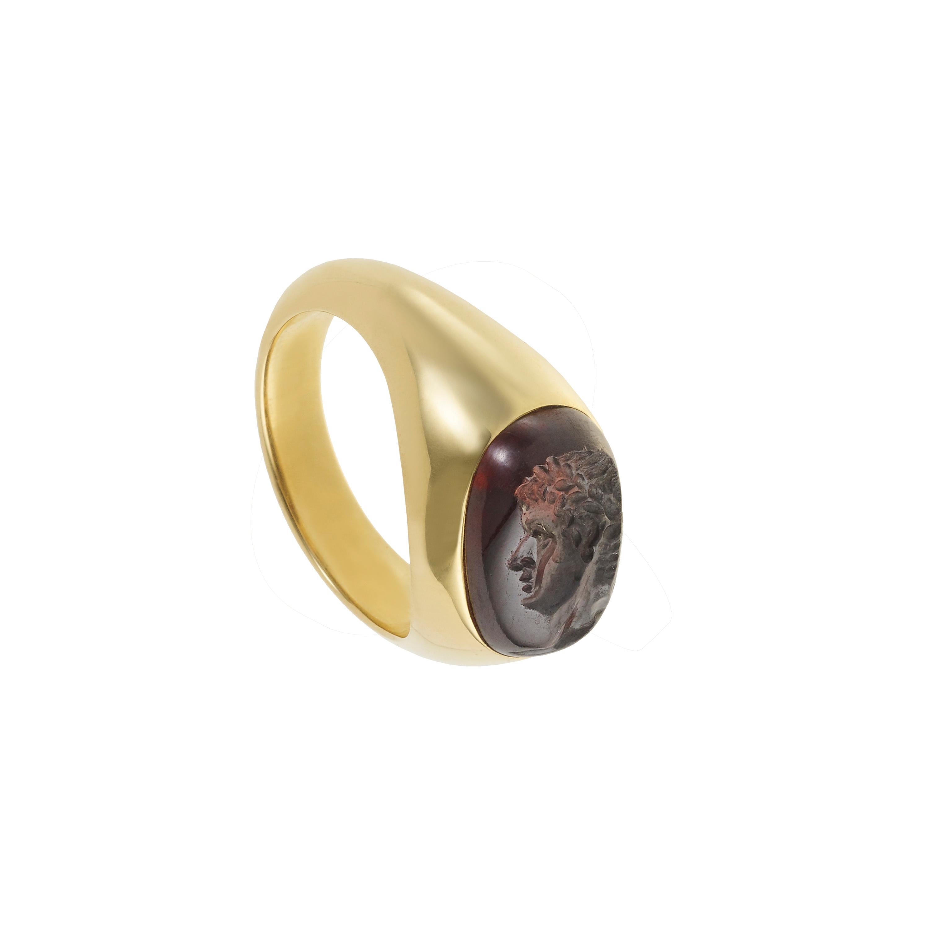 Victoria Strigini (née en 1991)

Bague contemporaine en or jaune 18 carats, ornée d'une intaille romaine en grenat cabochon du IIe-IIIe siècle ADS, sertie dans une monture moderne arrondie d'une pureté saisissante. Un jeune homme couronné au