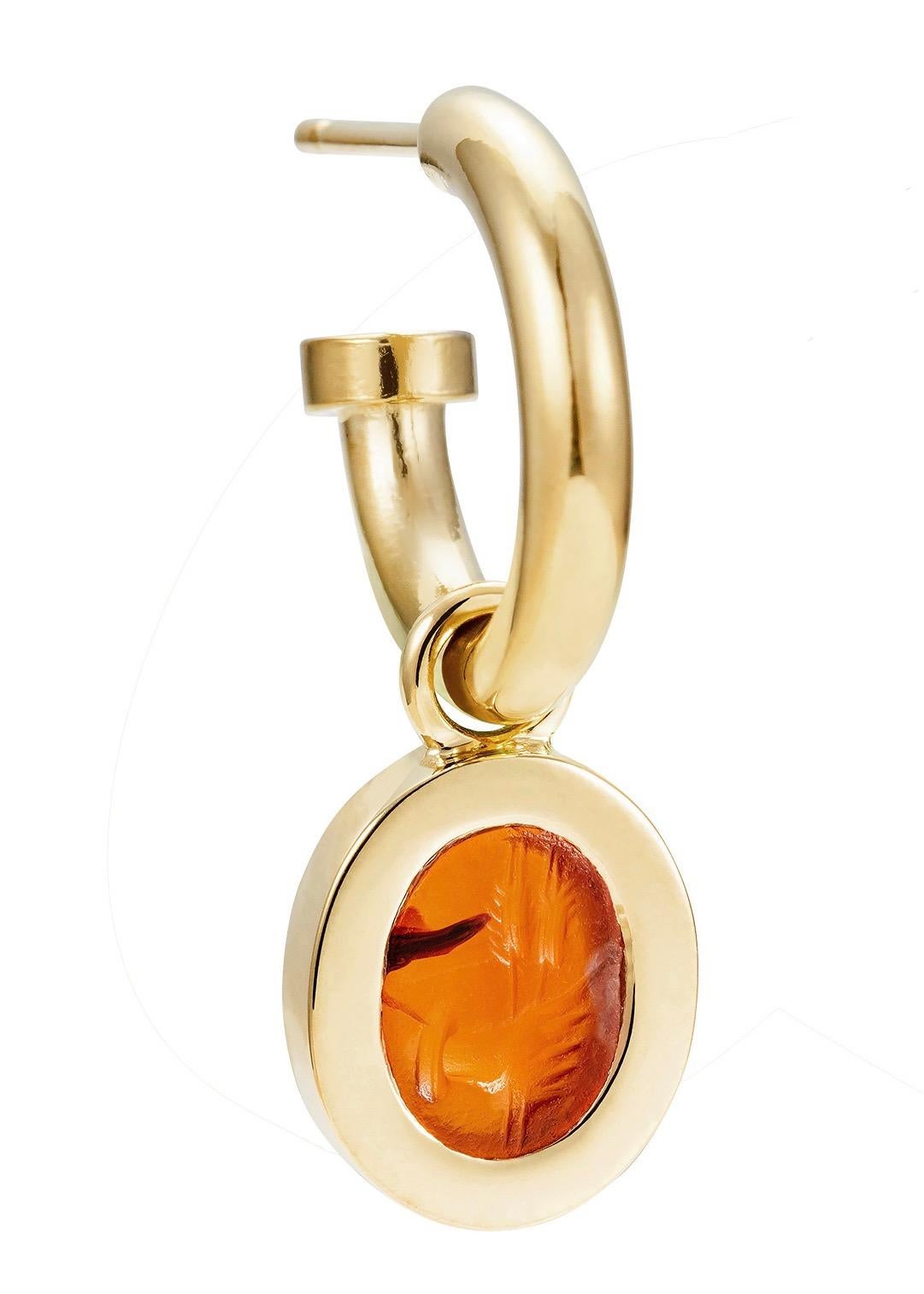 Victoria Strigini (b. 1991) 

An arresting pair of contemporary 18k yellow gold hoop earrings, with a single charm featuring an ancient Roman intaglio from the 2nd – 3rd century AD, in carnelian. The carnelian intaglio, in a bold and luminous