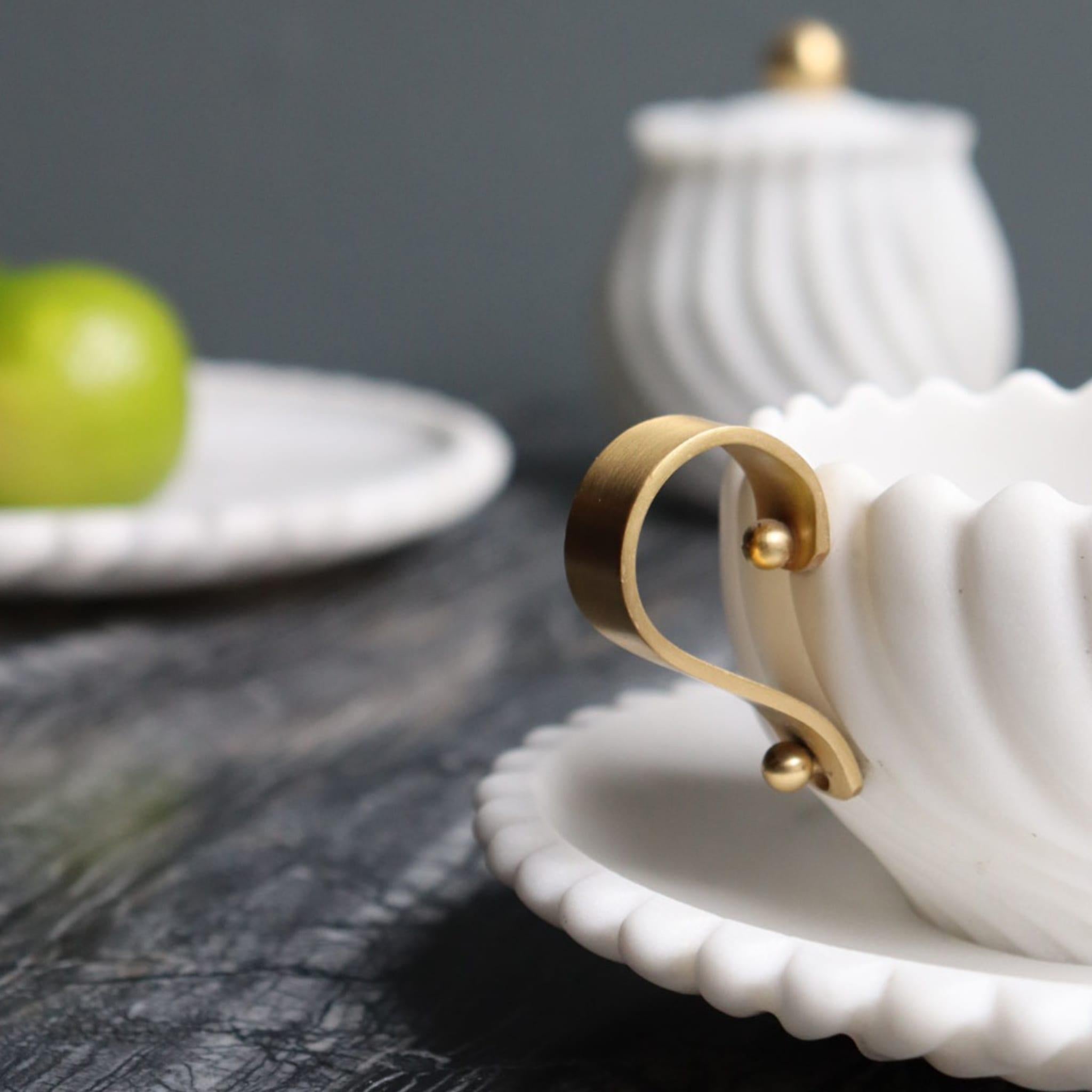 Diese bezaubernde Teetasse mit Untertasse ist Teil des Teesets Victoria, das von der britischen Nachmittagstee-Tradition inspiriert ist und aus Arabescato-Marmor handgefertigt wurde. Der ikonische Edelstein verleiht diesem Schmuckstück einen