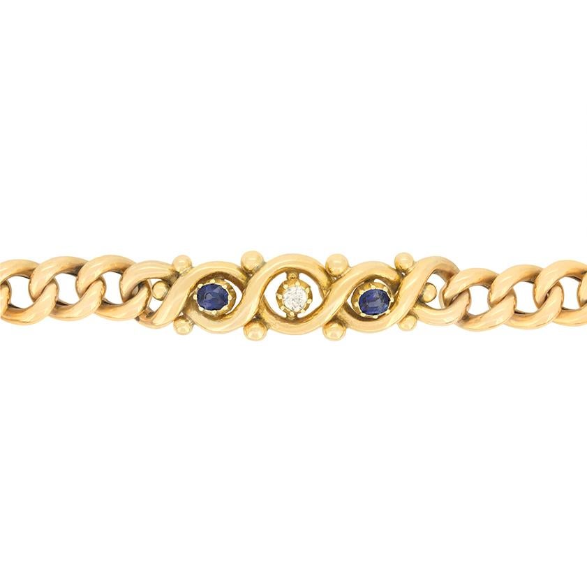 Esta maravillosa pulsera victoriana de oro de 15 quilates capta la esencia de la época. En el centro de la pulsera hay un brillante diamante talla antigua de 0,20 quilates, flanqueado a ambos lados por dos llamativos zafiros de talla ovalada, cada