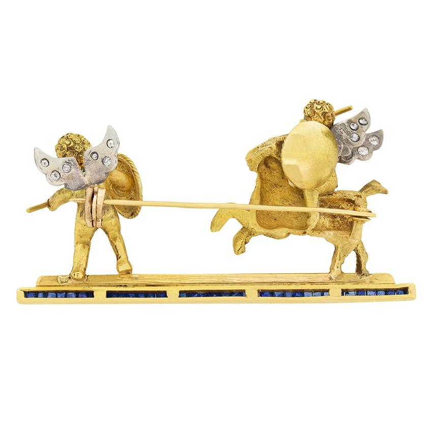 This playful Victorian Brooch depicts quarrelsome pair of cherubs. One cherub is seated on a goat, while each cherub raises an arrow. They are crafted out of 18 carat yellow gold, with wings accented by 0.30 carat of eight-cut diamonds. They are set