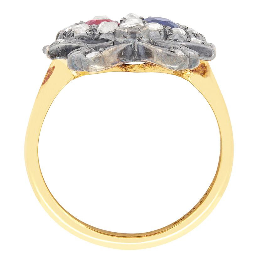 Cette ravissante bague victorienne à double cœur couronné présente un motif romantique de deux cœurs entrelacés avec deux belles pierres précieuses en leur centre, un rubis de 0,35 carat et un saphir de 0,35 carat. Les pierres sont entourées de