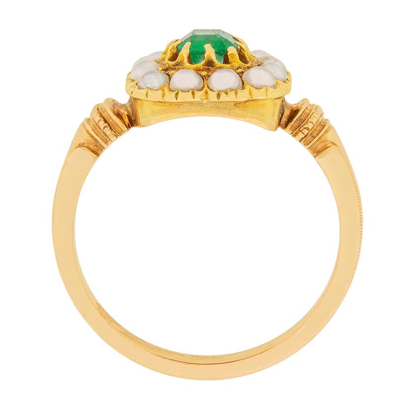 A green emerald is the centre of this lovely French Victorian era ring. The emerald is 0.40 carat, and is emerald cut. The gem is surrounded by a halo of 12 lustrous white seed pearls, contrasting the green of the emerald beautifully. The setting is