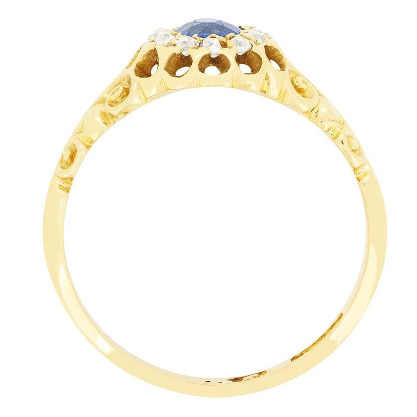 Dieser Ring aus den 1880er Jahren versprüht viktorianischen Charme mit einem leuchtenden Saphir von 0,40 Karat in der Mitte. Der oval geschliffene Stein ist in Gold gefasst und von einem Cluster aus altgeschliffenen Diamanten von insgesamt 0,80