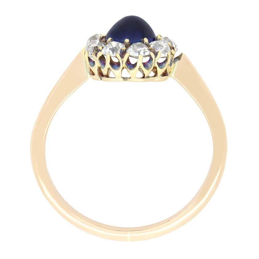 Mit einem natürlichen Saphir im Cabochon-Schliff in der Mitte ist dieser wundervolle viktorianische Ring ein einzigartiger Fund. Der zentrale Saphir wiegt 0,50 Karat und ist in 18 Karat Gelbgold gefasst. Der zentrale Stein wird durch eine Gruppe von