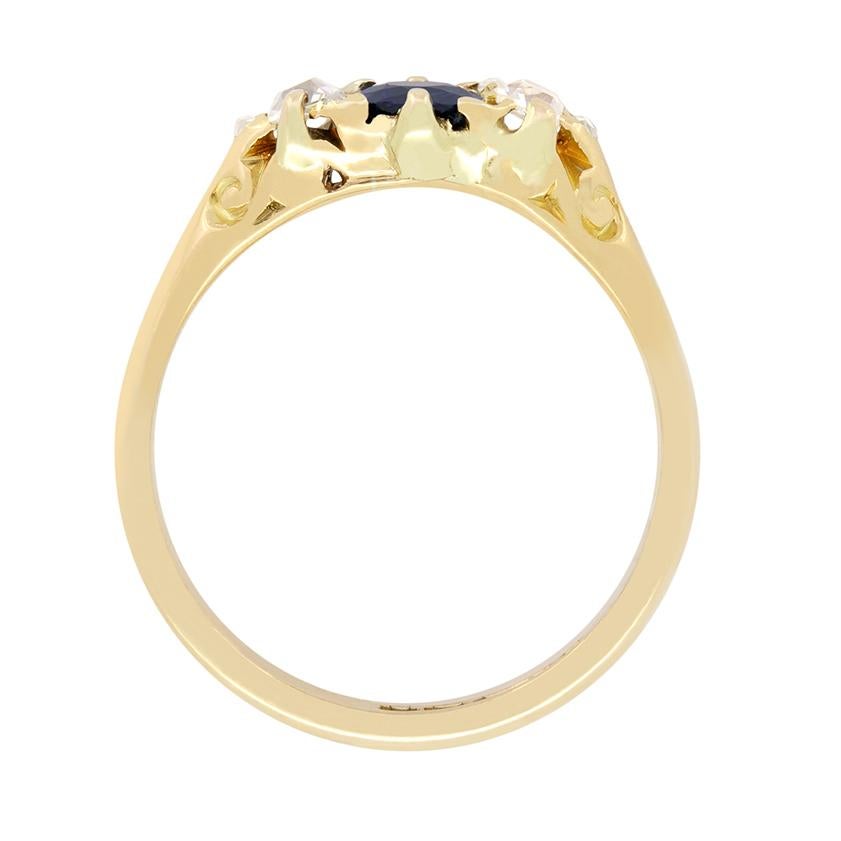 Dating to the 1880s in the height of the Victorian era, this beautiful three stone ring features a deep blue central sapphire flanked by diamonds. The Sapphire is an old cut stone weighing 0.50 carat. The flanking diamonds are old cushion cut