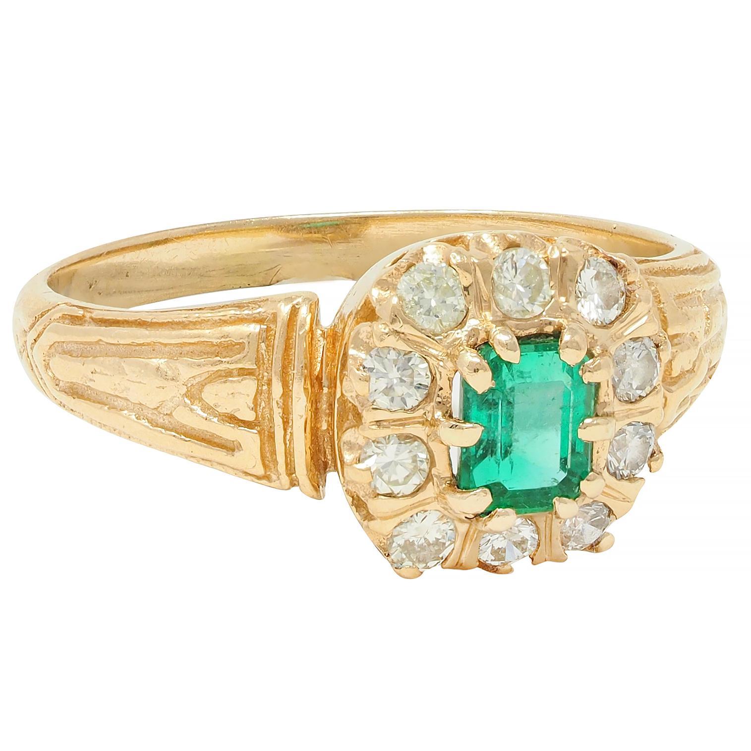 Centering an emerald cut emerald weighing approximately 0.35 carat total 
Transparent vibrant medium green in color - prong set
With a recessed halo surround of old European cut diamonds 
Weighing approximately 0.30 carat total - eye clean and