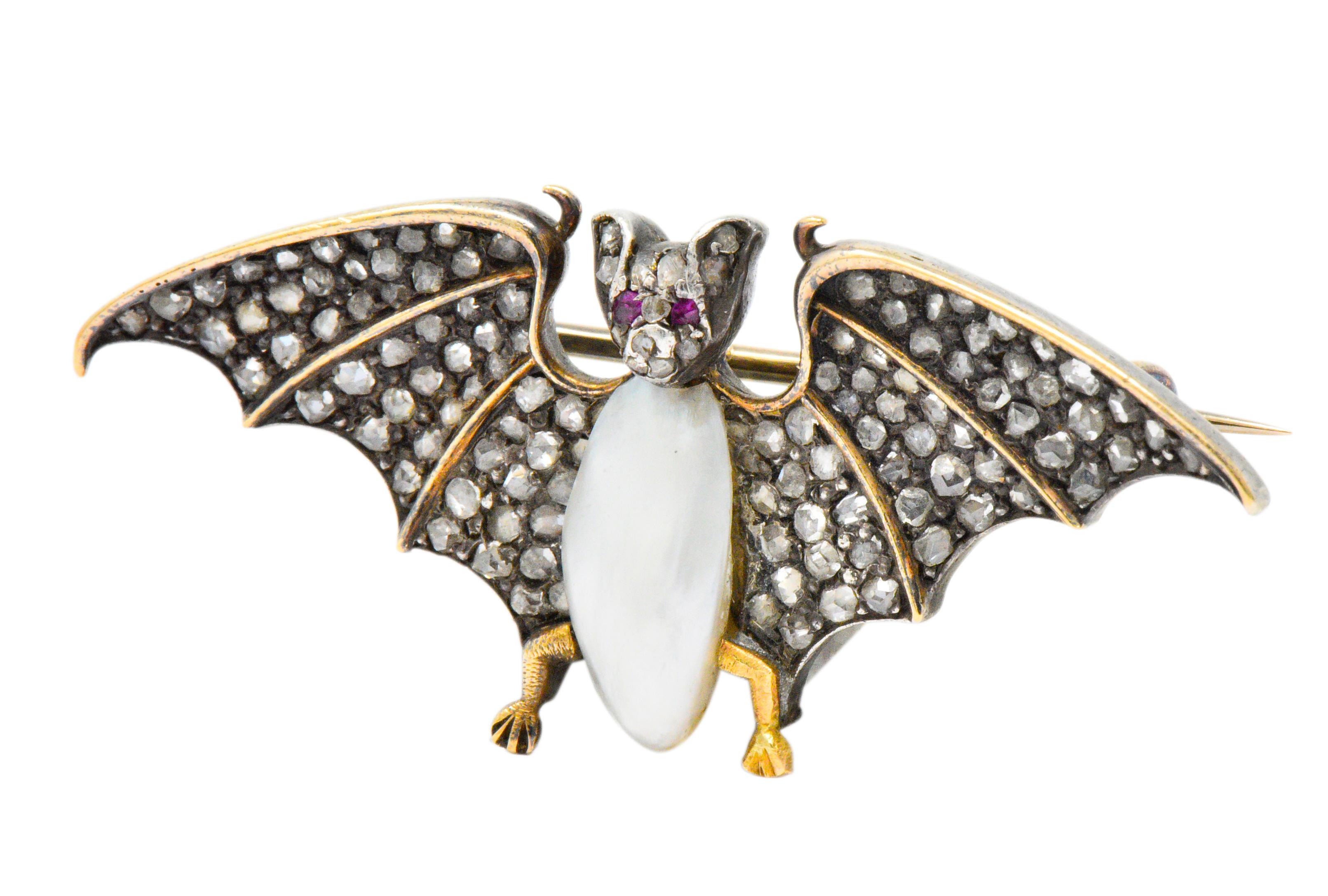 Unique winged bat whose wings and face contain pavé set rose cut diamonds, weighing approximately 0.75 carats total

Featuring a baroque freshwater natural pearl measuring 12.3 x 6.2 mm white body color and very good luster

Round cut ruby