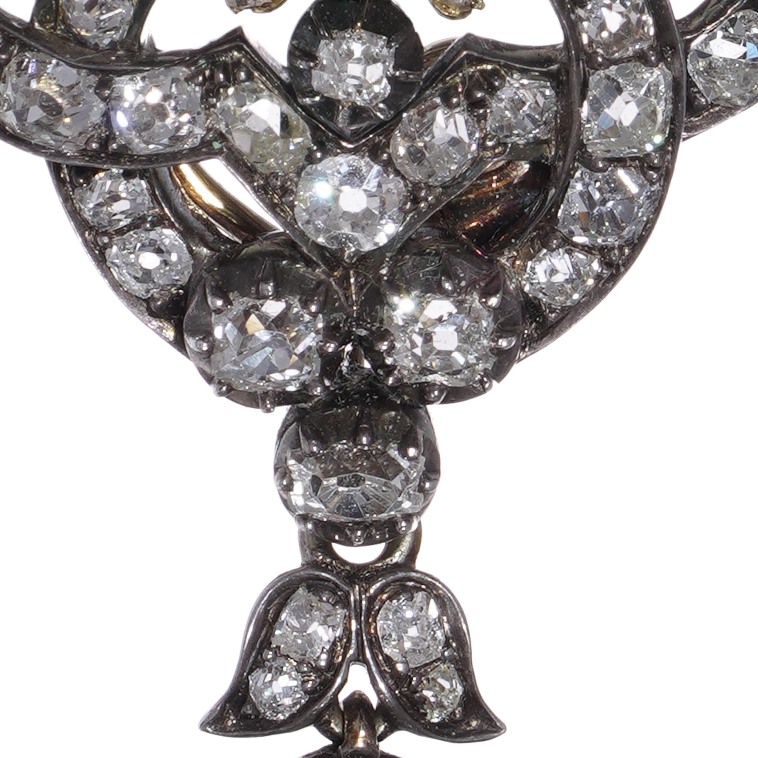 Pendentif victorien orné de la fin du 19e siècle, fabriqué en or 9kt avec une façade en argent, centré sur une émeraude vibrante d'environ 0,75 carats (aucune indication de traitement), entourée d'un motif élaboré de feuillage et de volutes serti