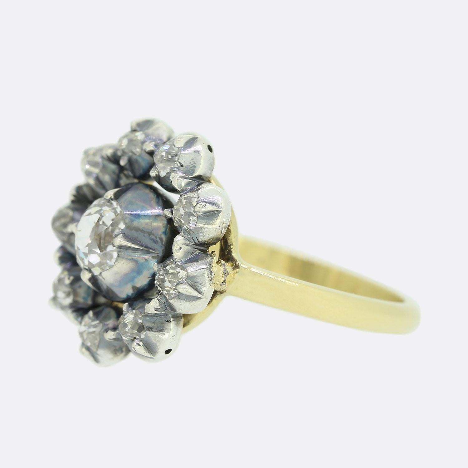 This is a beautiful, 18ct yellow gold diamond cluster ring. The ring features a central old mine cut diamond and is surrounded by nine smaller old cut diamonds in a cluster style. The diamonds are silver set in cut down collet mounts and this leads