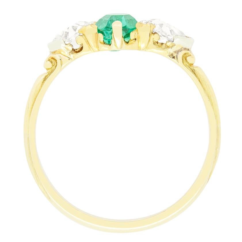An enchanting natural emerald is flanked by vertically set old oval cut diamonds in this wonderful Victorian three stone ring. The central emerald is also an oval cut stone weighing 0.90 carat. The accompanying diamonds ate 0.40 carat a piece with