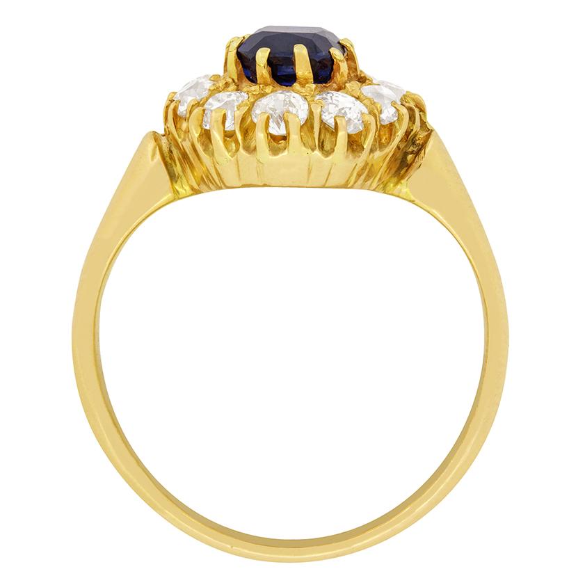 This ring from the Victorian era features a beautiful dark blue, old cushion cut Sapphire in its centre. The Sapphire is 0.95 carat and firmly claw set within the hand crafted 18 carat yellow gold ring. A halo of old cut diamonds, totalling 1.00