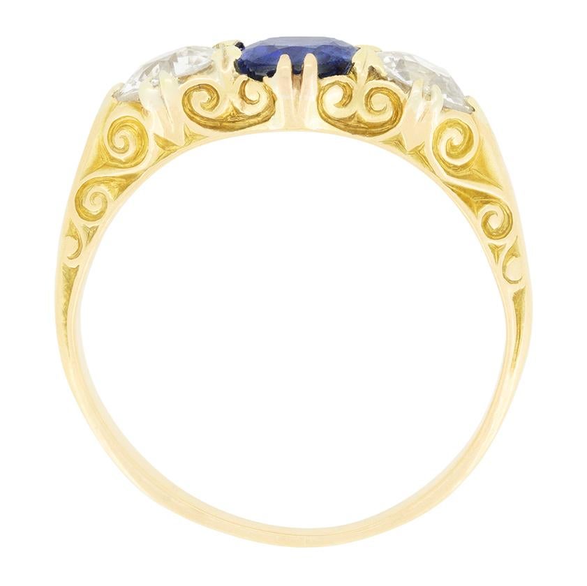 Cette magnifique bague trilogie à tige sculpt�ée date de l'époque victorienne. Au centre de la scène, un saphir de taille ovale est flanqué de deux diamants de taille ancienne. Le saphir central pèse 1.00 carat et est une pierre naturelle non