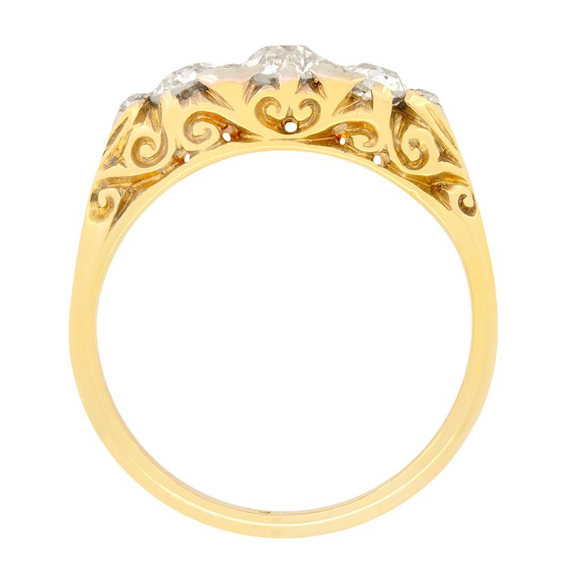 Cette magnifique bague victorienne met en valeur trois diamants de taille ancienne dans une monture sculptée. Le diamant central est de 0,50 carat, tandis que les diamants de chaque côté sont de 0,25 carat chacun. De petits diamants de taille rose