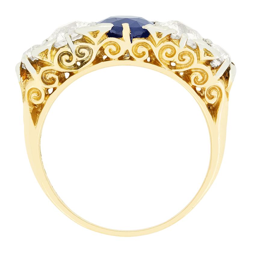 Cette bague victorienne enchanteresse présente un saphir central flanqué de diamants de taille ancienne. Le saphir central pèse 1,05 carat et est une pierre entièrement naturelle. Les deux diamants de chaque côté pèsent 0,65 carat, avec un diamant