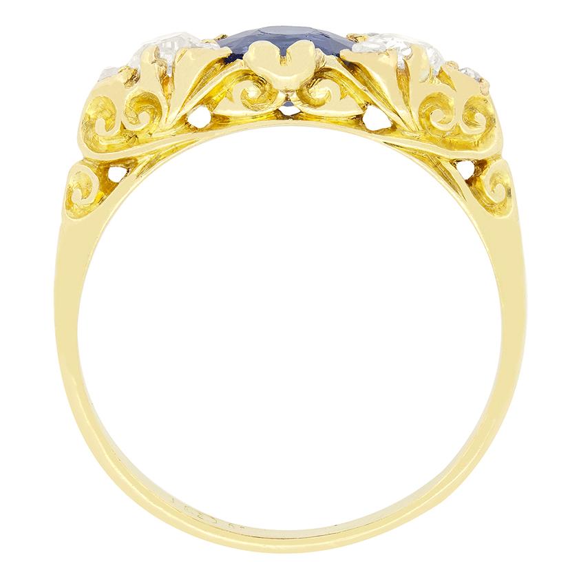 Un magnifique saphir bleu naturel et non chauffé trône fièrement au centre de cette bague trilogie victorienne, flanquée de diamants taillés dans des mines anciennes. Le saphir central est une pierre de taille ovale pesant 1,05 carat, tandis que les