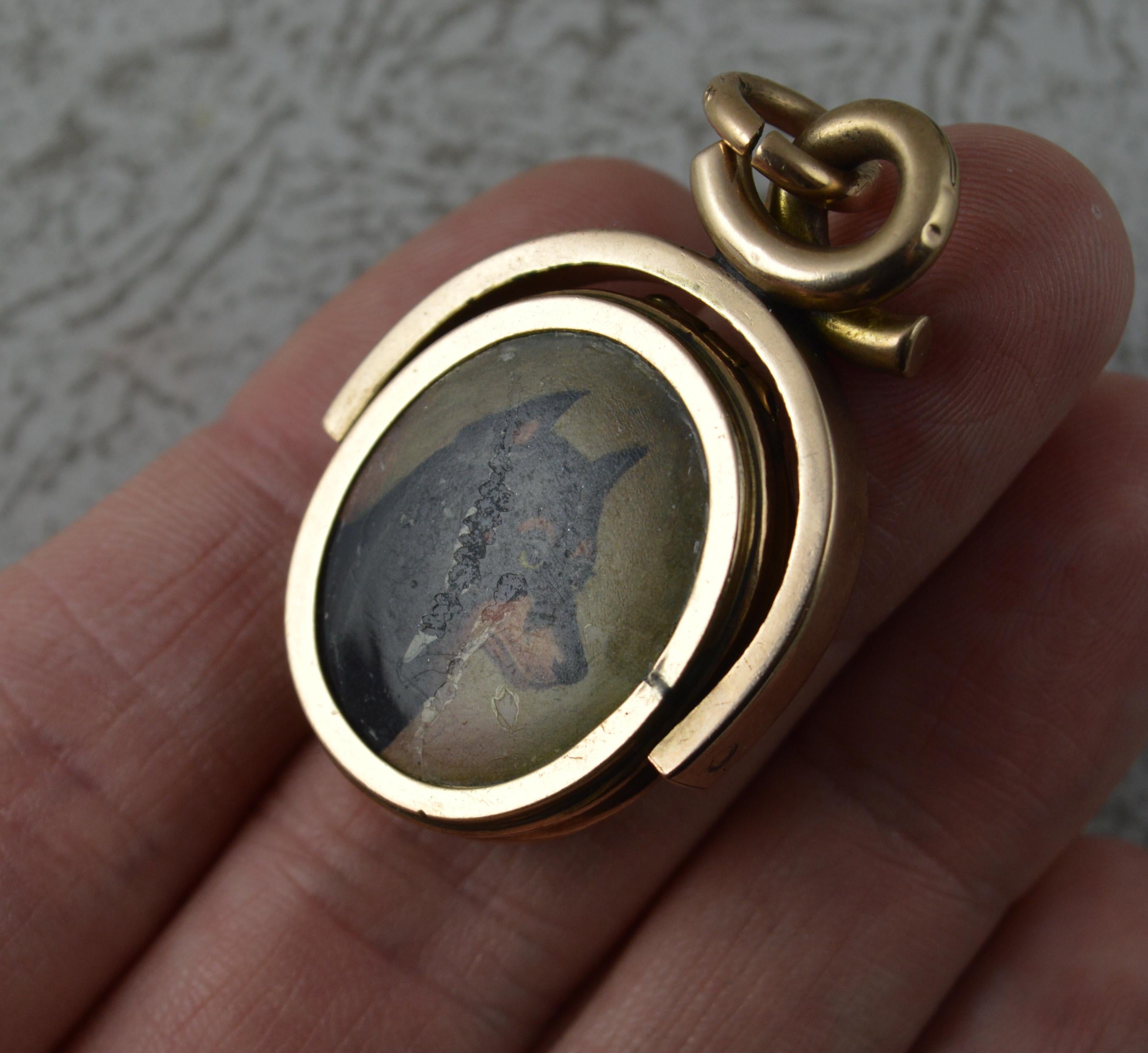 A fantastic Victorian period swivel fob pendant locket.
Modelled in 10 carat rose gold throughout. Stylish shape and design.
Designed with a large oval shaped carnelian to one side and hand painted plaque of a dog to the other which opens up to
