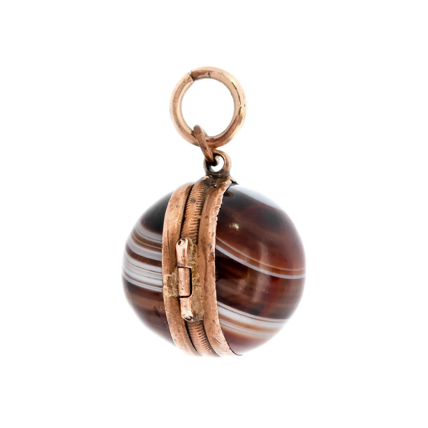 A lovely banded agate locket from the Victorian (ca1880) era! This beautiful orb-shaped piece is crafted in 10k yellow gold and displays two sides of rich banded agate. The agate faces are smoothly polished and display an incredibly beautiful