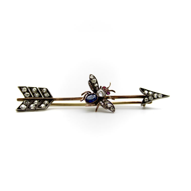 This Victorian brooch contains a plethora of diamonds and gemstones in a variety of beautiful antique cuts. Shaped like an arrow, and topped with a gemstone-encrusted fly, the brooch is an unusual combination of Victorian motifs. The thorax of the