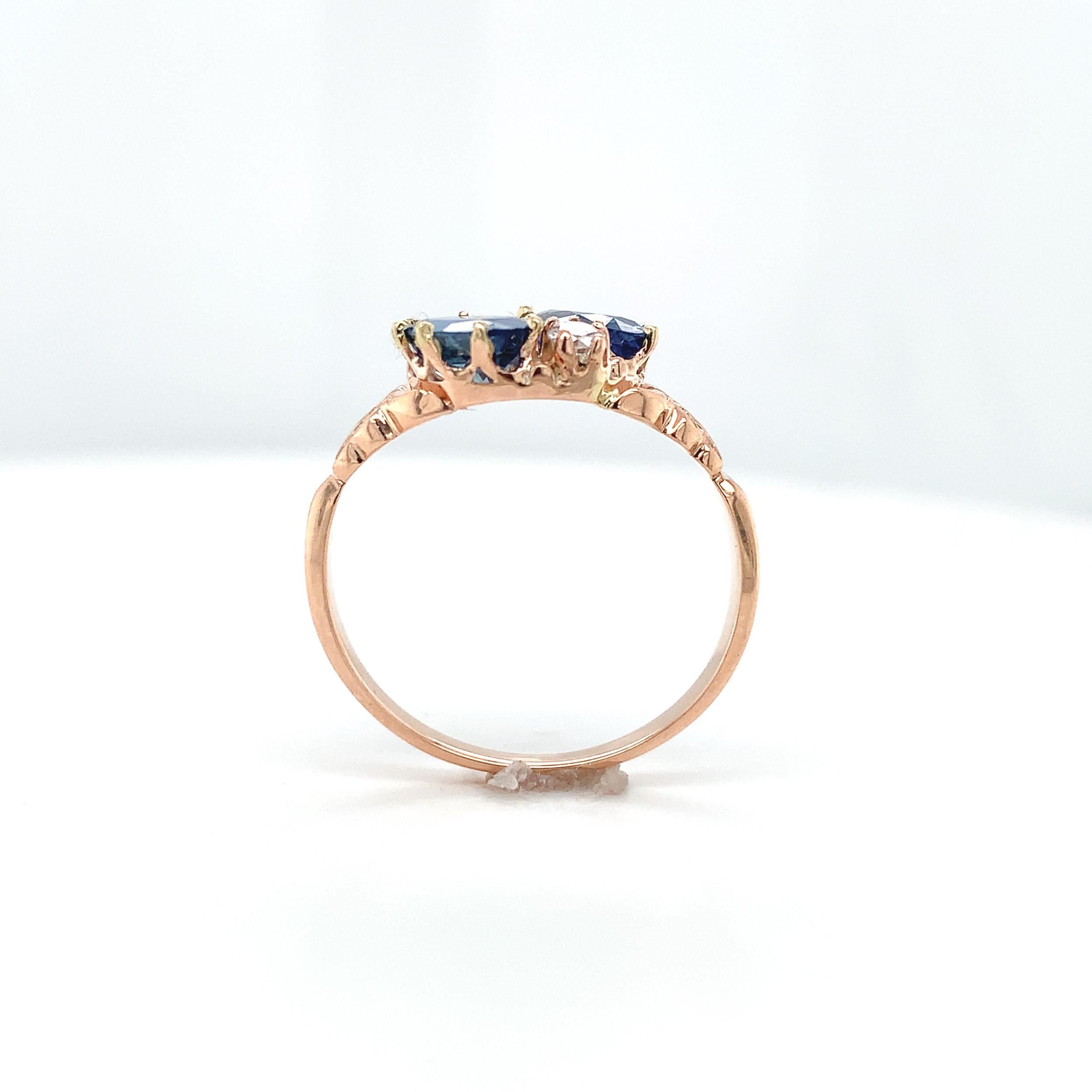 Victorian 10K rose gold ring featuring 2 oval blue sapphires.  The sapphires weigh 1.65 carats total. The sapphires are medium dark color and measure about 7mm x 5mm. There are 2 small round brilliant cut diamonds measuring about 2.2mm. The ring
