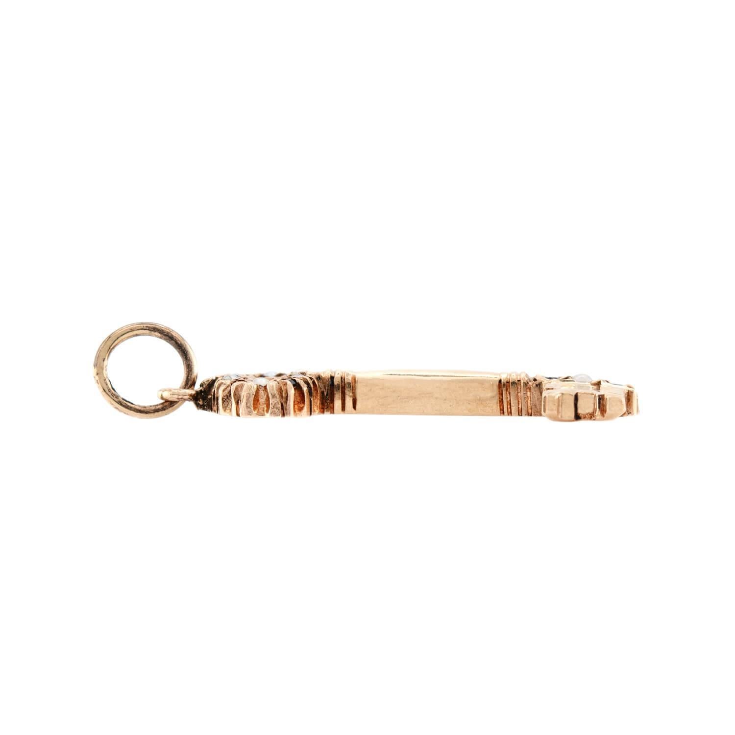 A darling key charm from the Victorian (ca1880s) era! Crafted in 10k yellow gold, this dainty charm resembles a small key. The top of the key is decorated with alternating sapphire and seed pearls, and all of the stones are held within small bead
