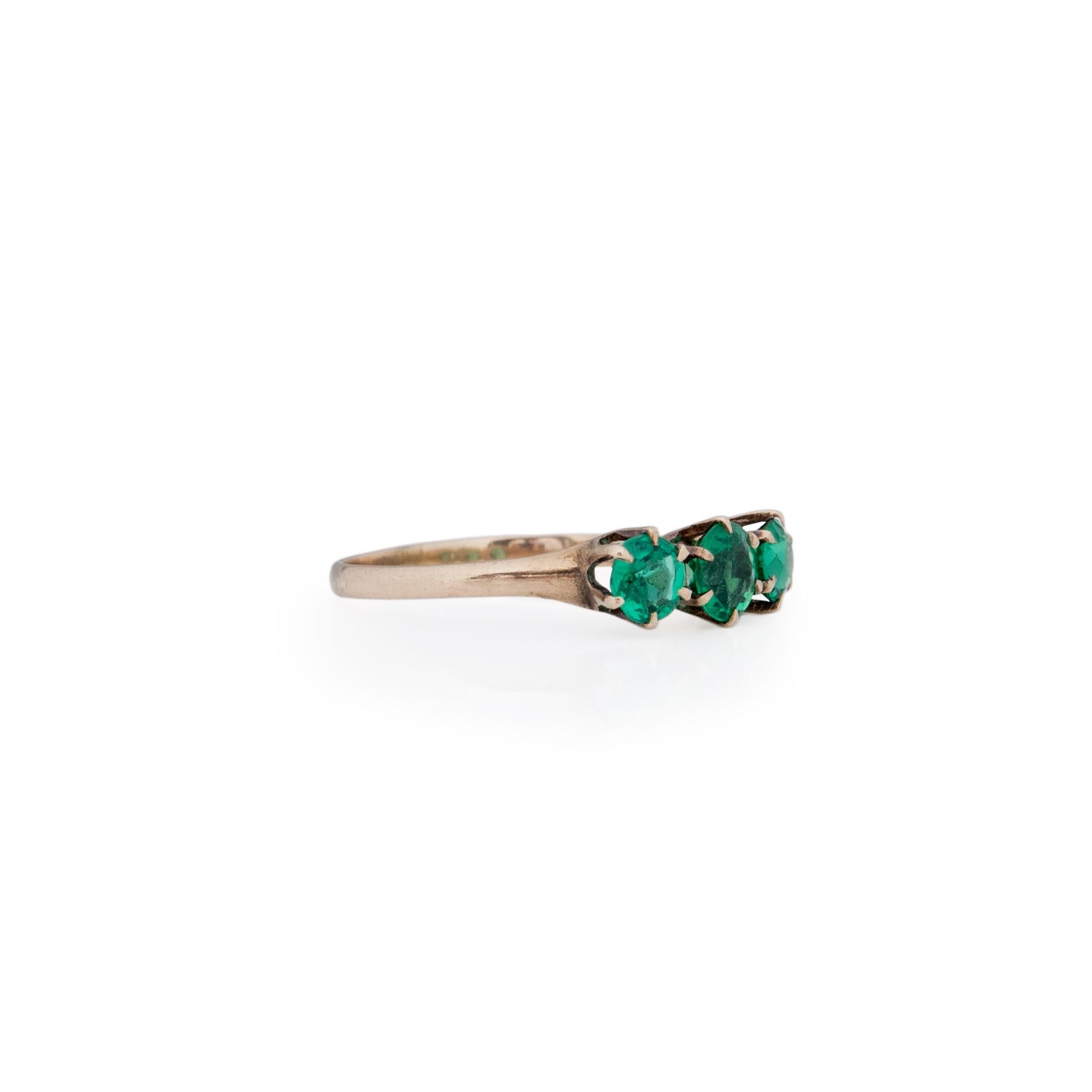 Looking for an authentic Victorian piece? This three stone beauty has excellent color. True to the era, this 10k yellow gold setting holds these green glass gems with six prongs each. The strait shank design allows all the focus to be on the center