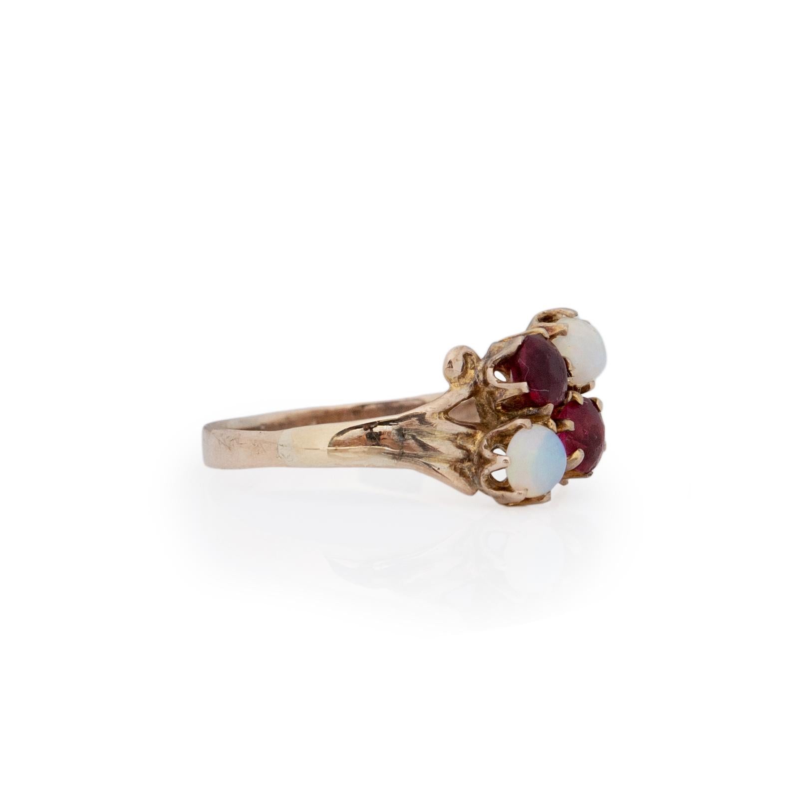 This antique Victorian treasure is crafted in 10K yellow gold. The split shank design is nearly a bypass design, in the center of the split shanks are two old cut garnet pieces and two opal cabochons. The delicate carved shanks are the perfect