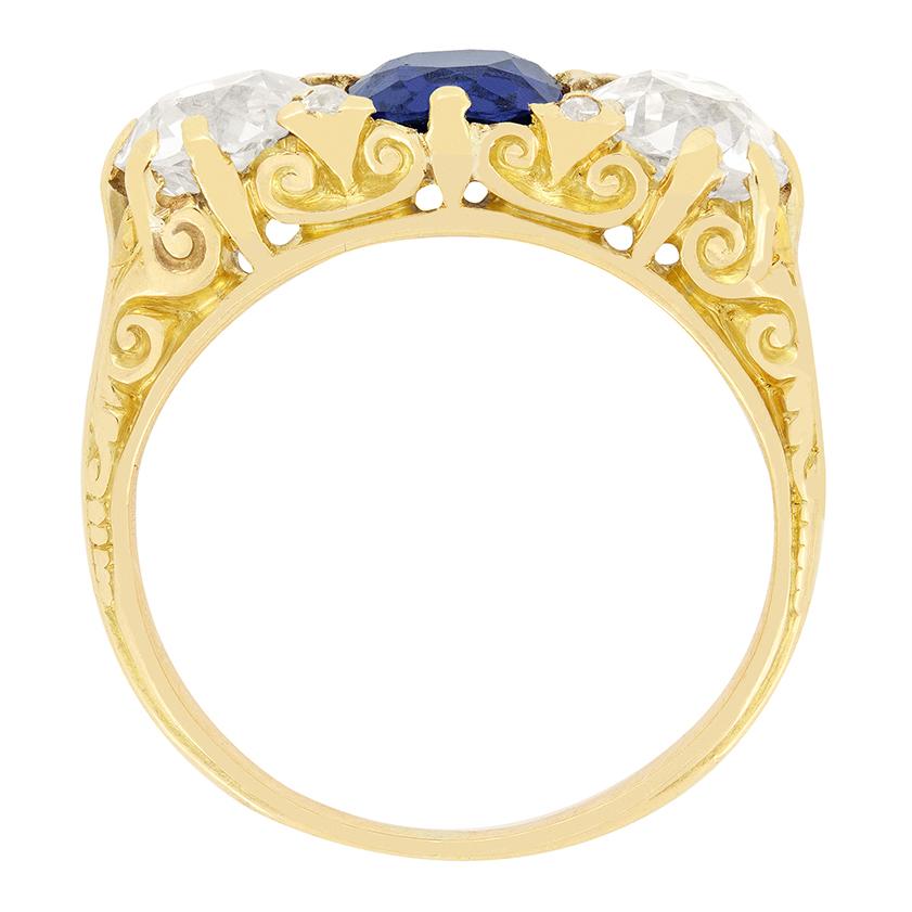 Dieser wunderschön geschnitzte Trilogiering stammt aus der viktorianischen Ära. Im Mittelpunkt steht ein lebendiger Saphir im Kissenschliff, der von zwei Diamanten im Altschliff flankiert wird. Dazwischen sind vier weitere Diamanten im Rosenschliff