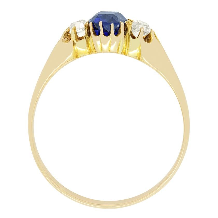 Un superbe saphir birman est flanqué de diamants de taille ancienne dans cette merveilleuse bague trilogie victorienne. Le saphir de 1,12 carat est une ancienne pierre taillée en coussin et a été certifié par GCS comme étant naturel et non chauffé.